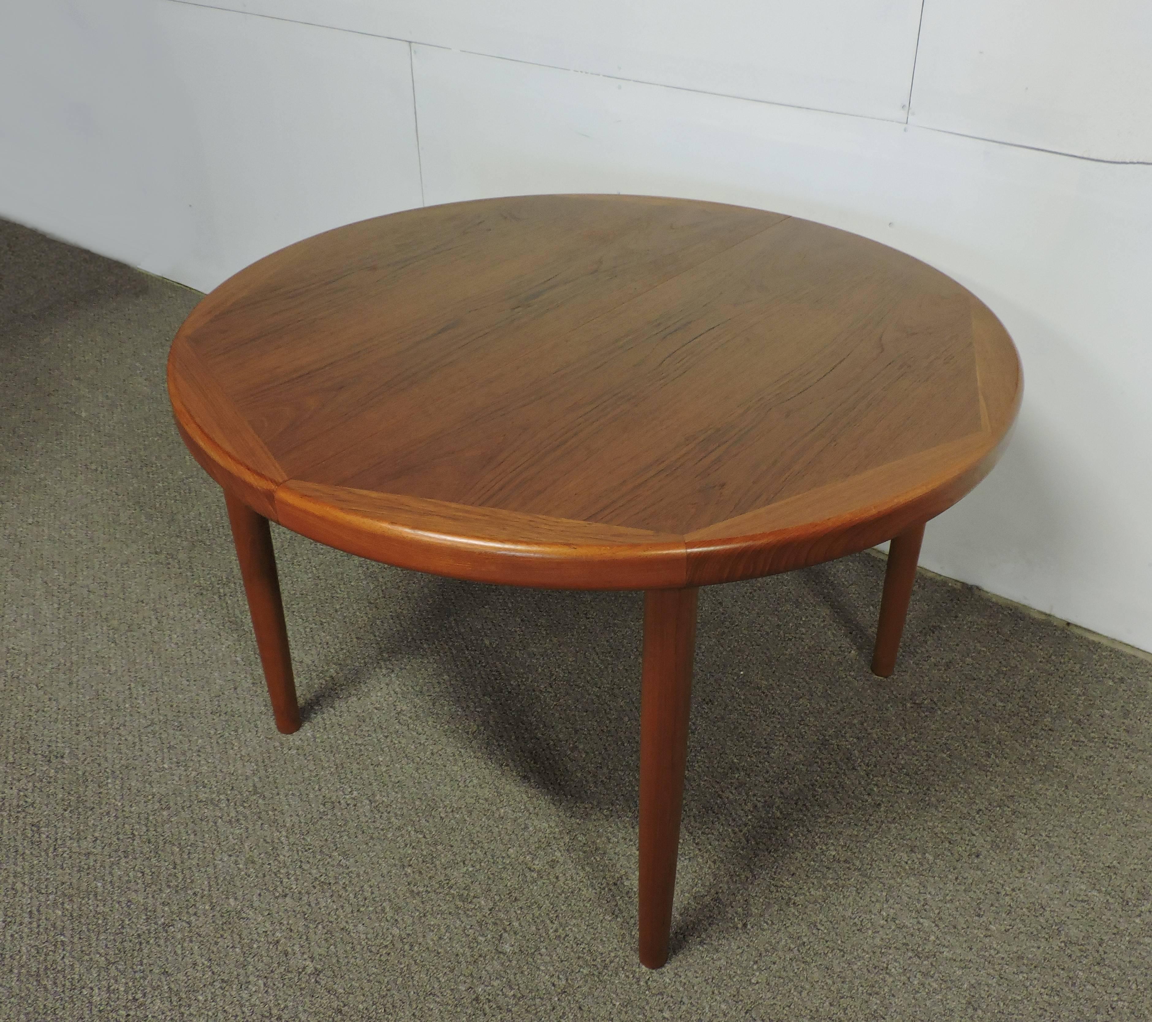 Wonderful teak dining table made in Denmark by Vejle Stole. This round dining table can extend to a large 86 inch long oval with the installation of two leaves. Solidly constructed, it has a beautiful wood grain pattern and four solid teak tapered