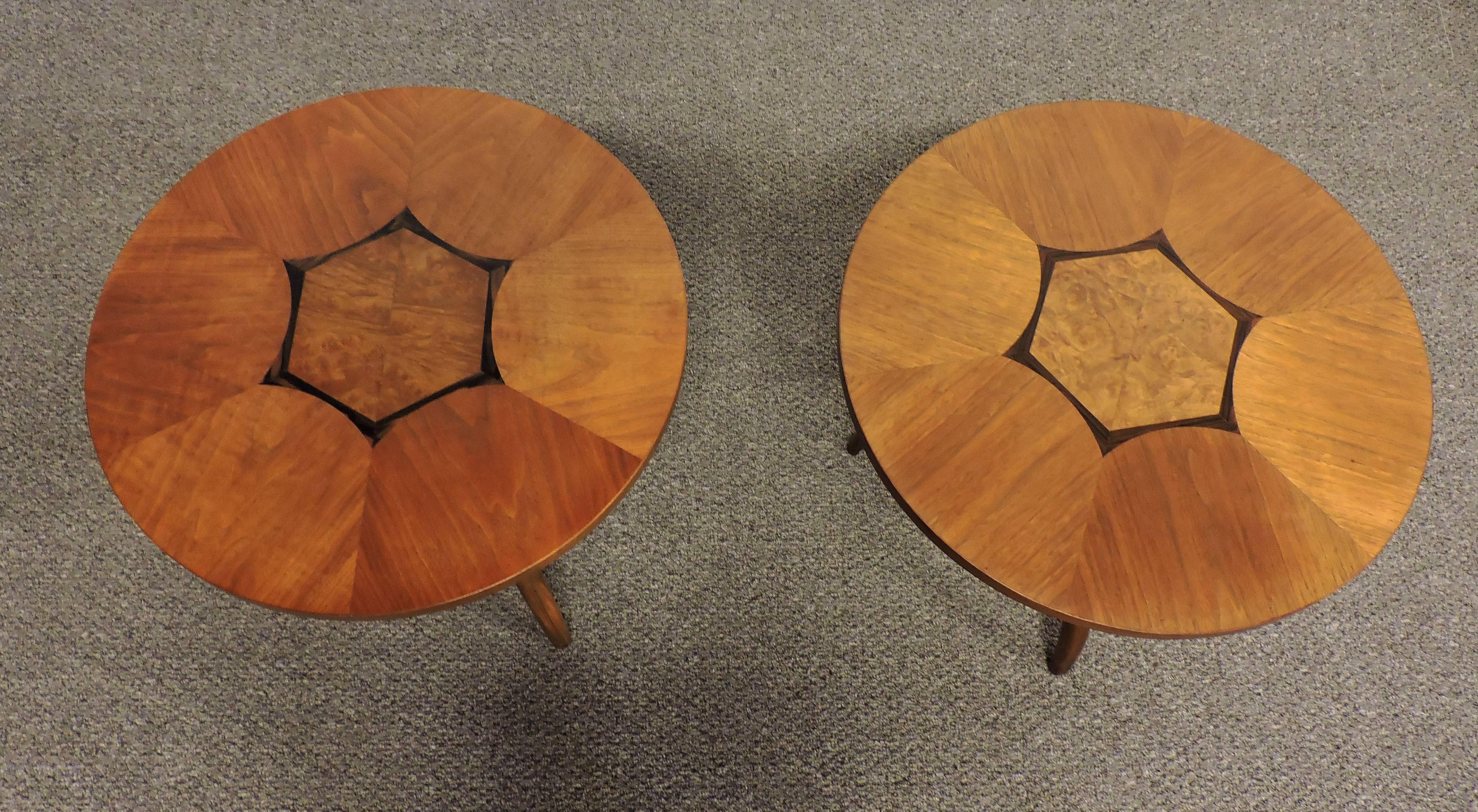 Beautiful pair of round walnut end tables made by high quality furniture manufacturer, Drexel. These tables have graceful curved tripod legs and a round inlaid wood top with a striking geometric design. Marked composite by Drexel on bottom.