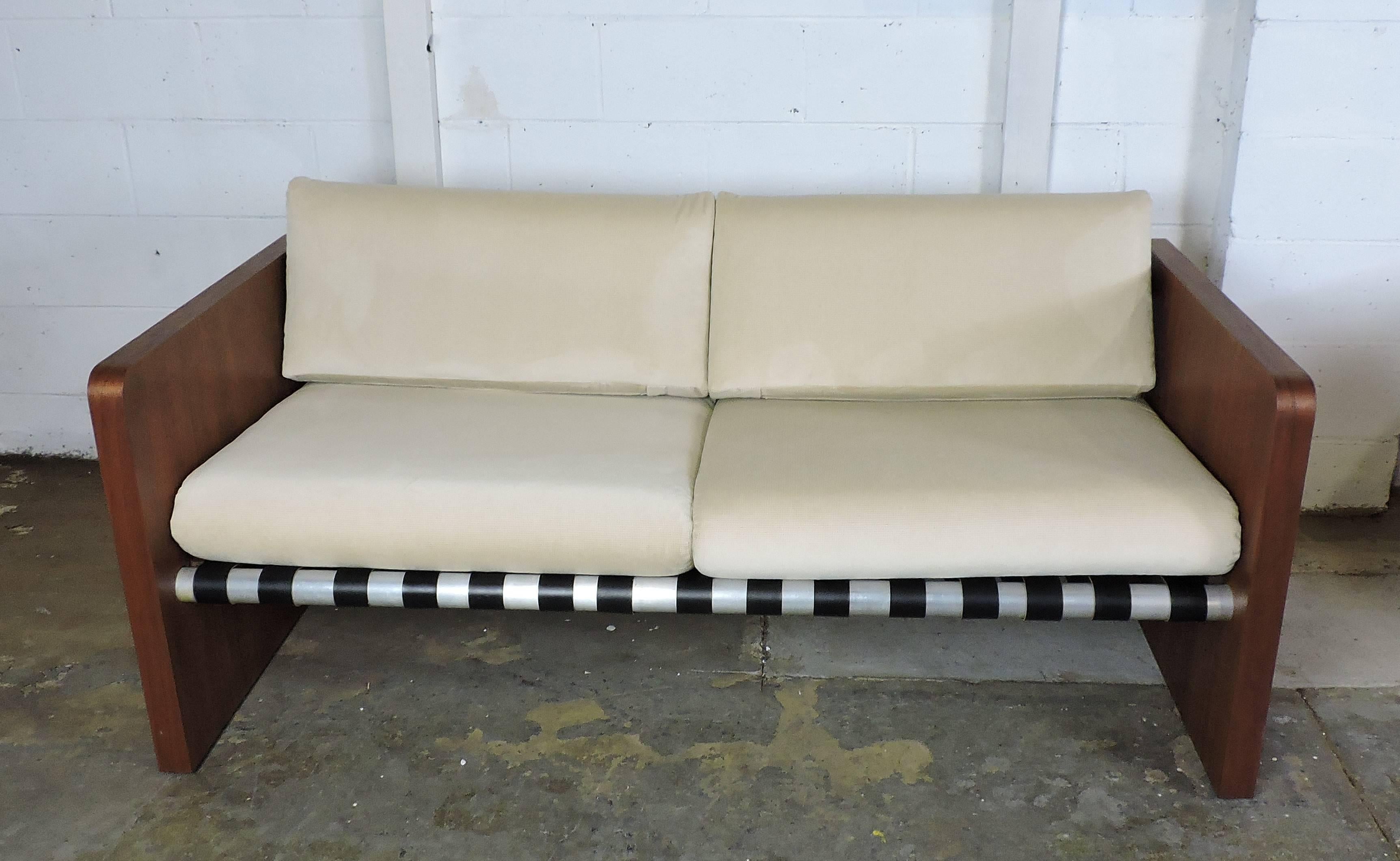 Fabulous pair of midcentury sling sofas manufactured by Founders Furniture Company. These sofas have a nice clean look with cushions that rest on black leather slings that are attached to three heavy-duty polished aluminum poles. The sides have
