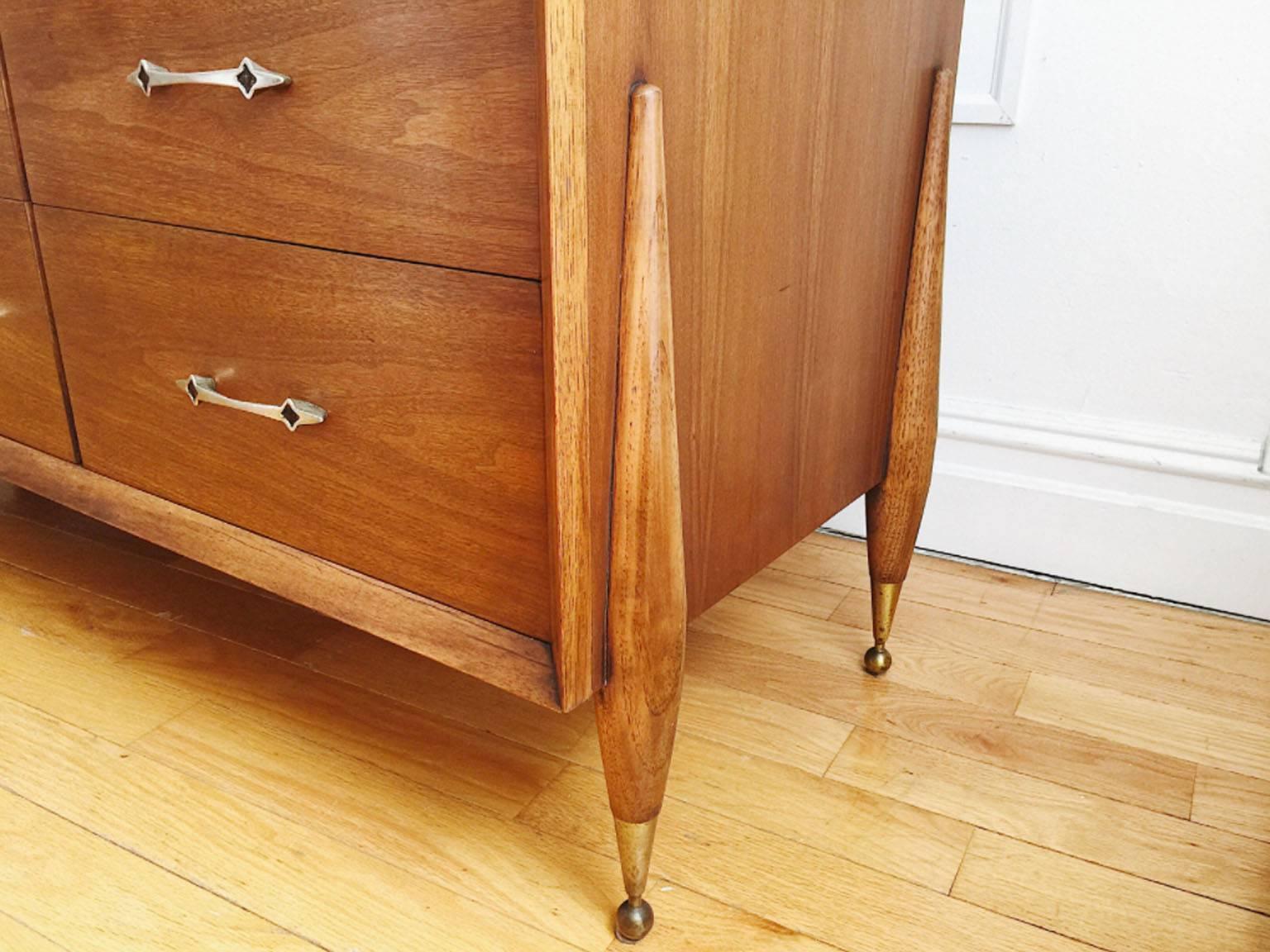 Danish-inspired, Mid-Century Modern lowboy triple dresser, credenza or sideboard from Kent Coffey's 'The Auburn' line. Original pulls, brass feet and walnut wood. In excellent vintage condition, drawers are all clean and slide easily. One minor