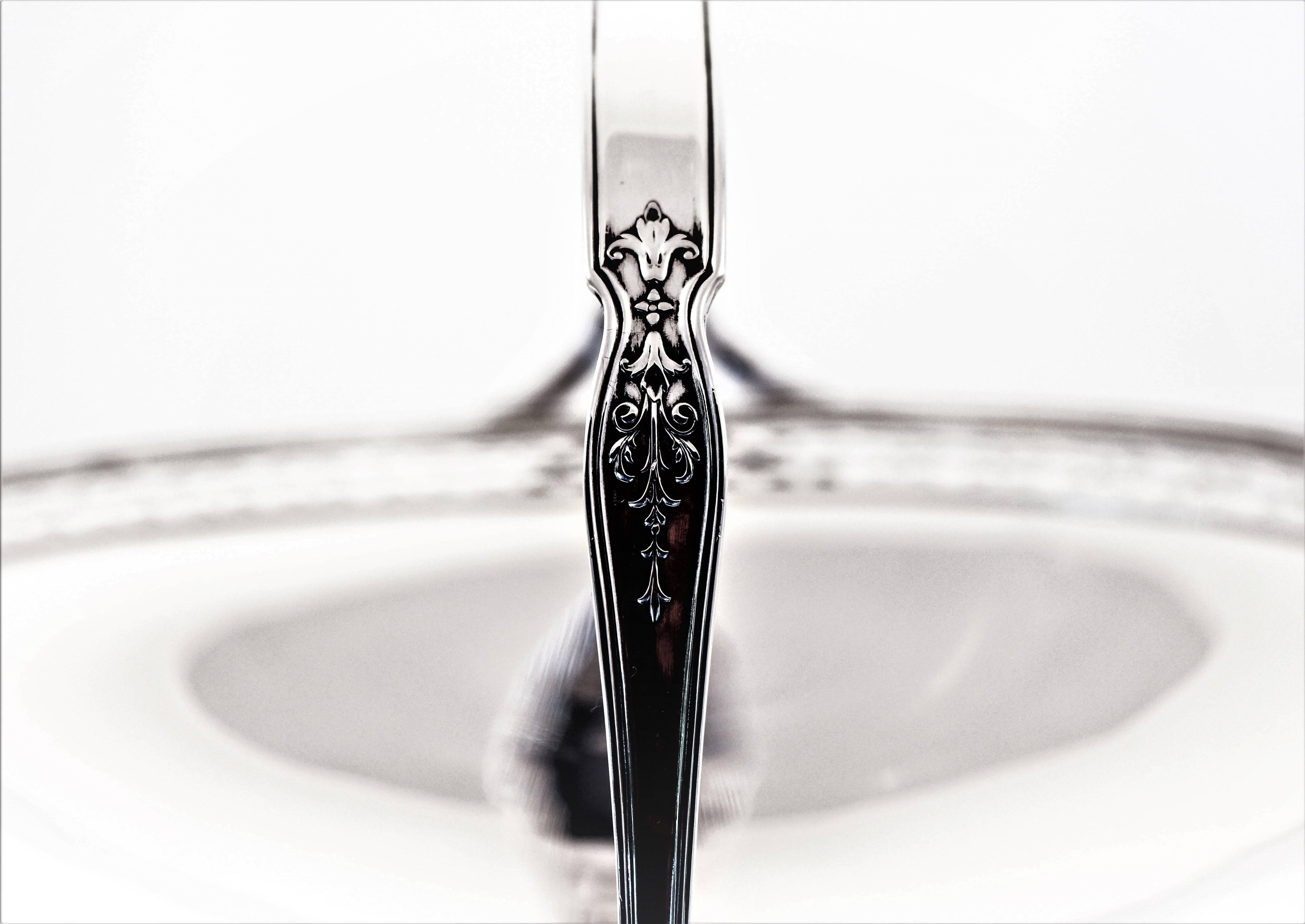 Sencilla pero elegante. Esta cesta se asienta sobre un pedestal, de modo que queda elevada de la superficie. Un bonito motivo recortado rodea el borde y el asa tiene una flor de lis a cada lado. Realmente genial para cualquier cosa, desde pasteles