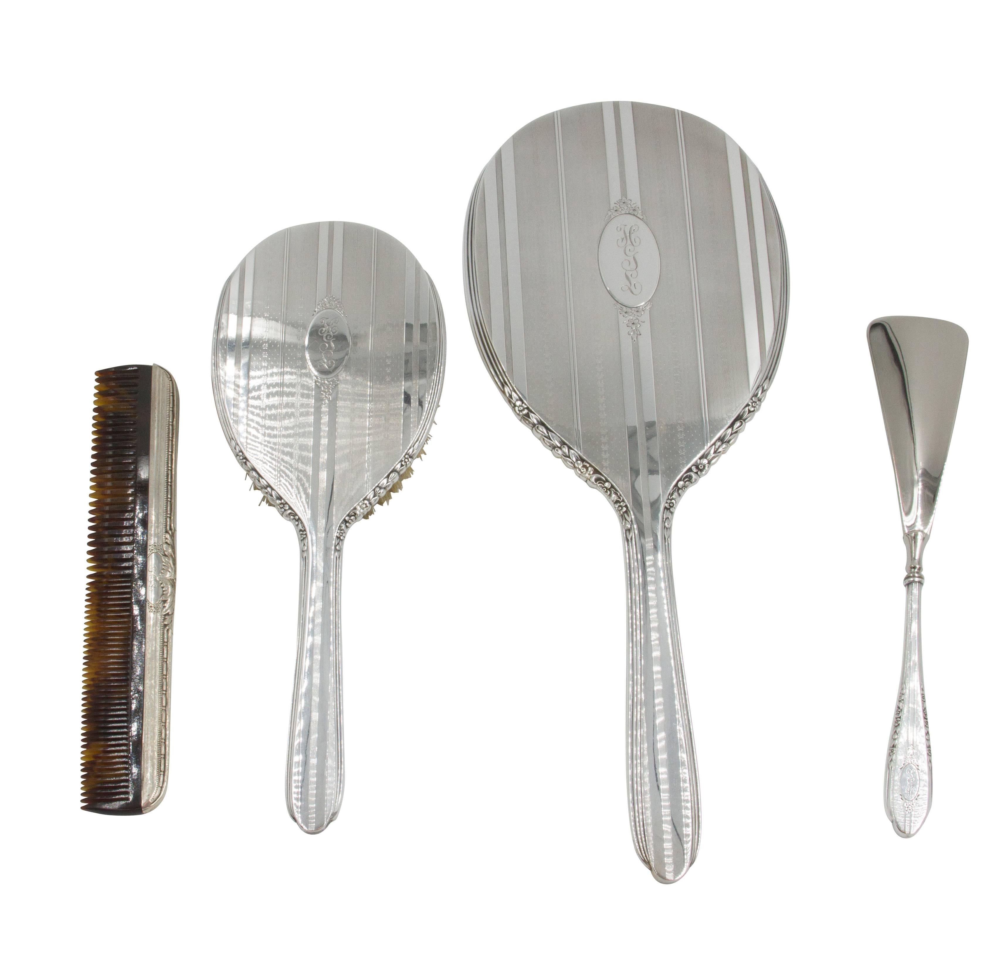 Being offered is a complete ladies vanity set in an Art Deco pattern. Pieces include; hand mirror and brush, large crystal powder jar, shoe Horn, nail file and buffer, new tortoiseshell comb, three brushes (two round and one oval). The silver has a