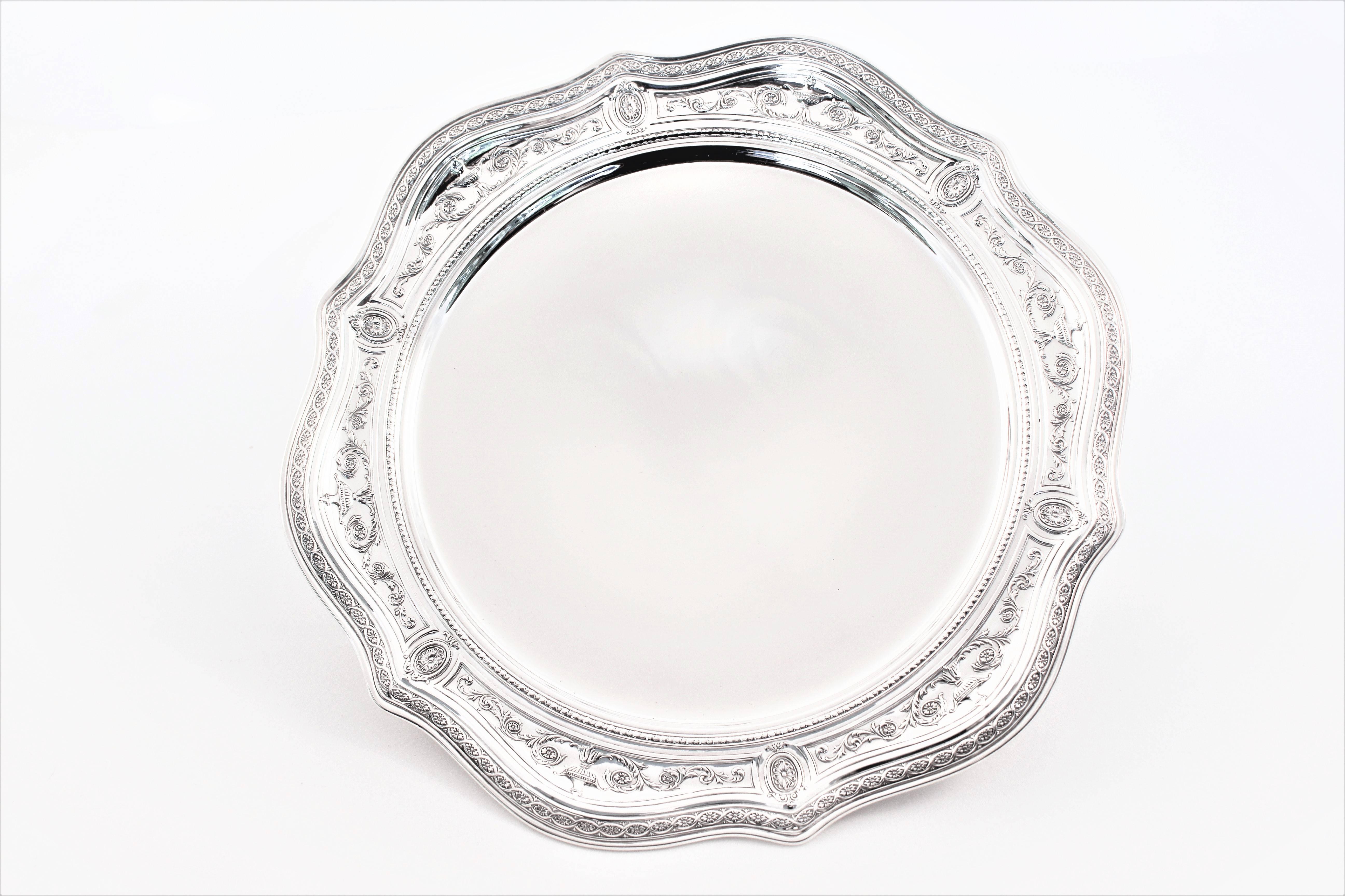 Proudly offering a pair of footed dishes by International Silver Co. A delicate design of medallions, urns and vines encircle the scalloped border. The dish sits on a pedestal thereby raising it off the surface. Although the rim has a design, it is
