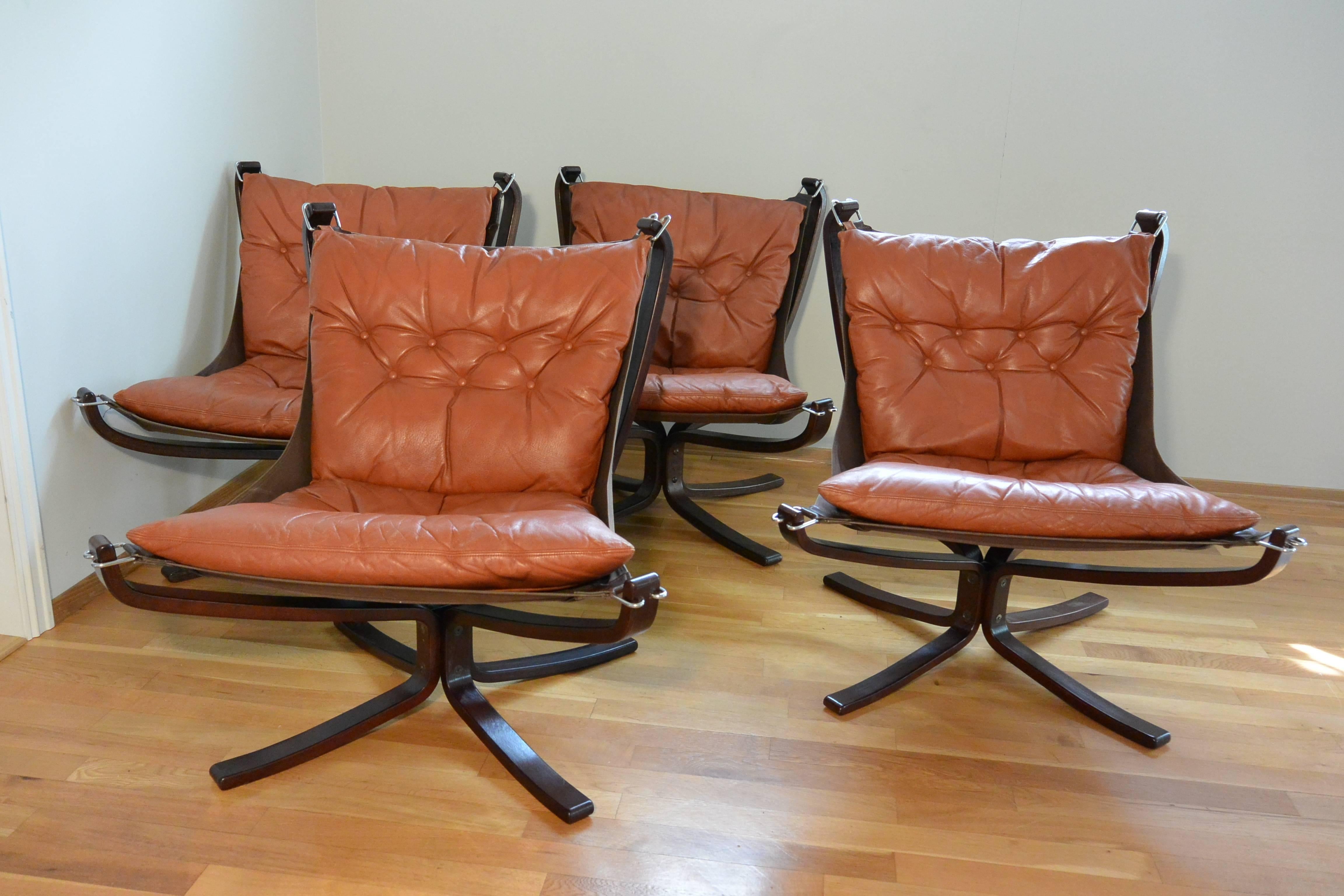 Falcon chair set of four in cognac leather and laminated rosewood frame. Designed by Sigurd Ressell fro Vatne Mobler, Norway.

The laminated rosewood frame legs are bolted at the base to a metal rectangular tube. The canvas attaches to the frame