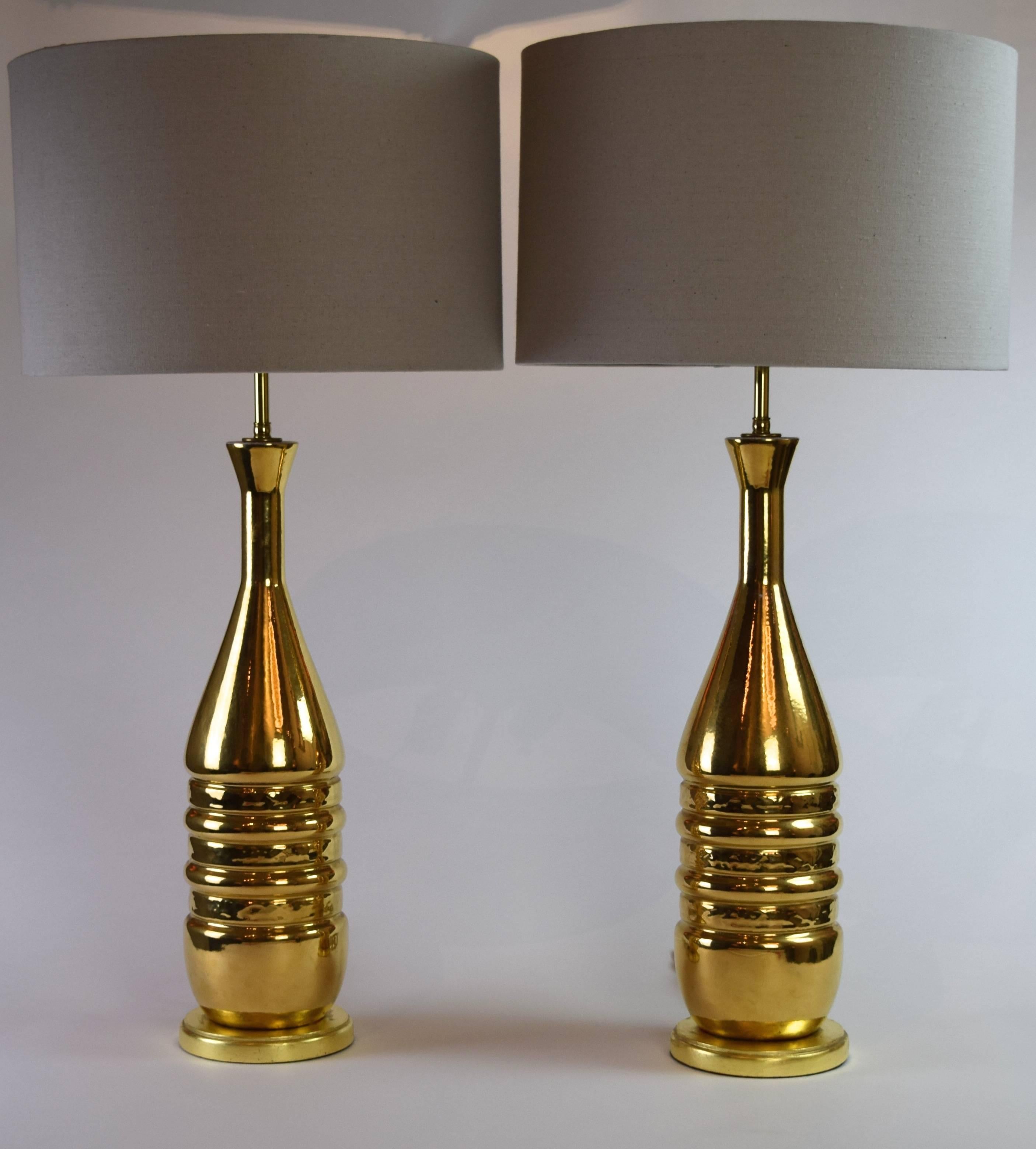 Each large table light is bottle-shaped with alternating concave and textured bands on circular giltwood bases.

Measures:" Height to base of light fitting: 21"
Height to top of finial: 33.5".