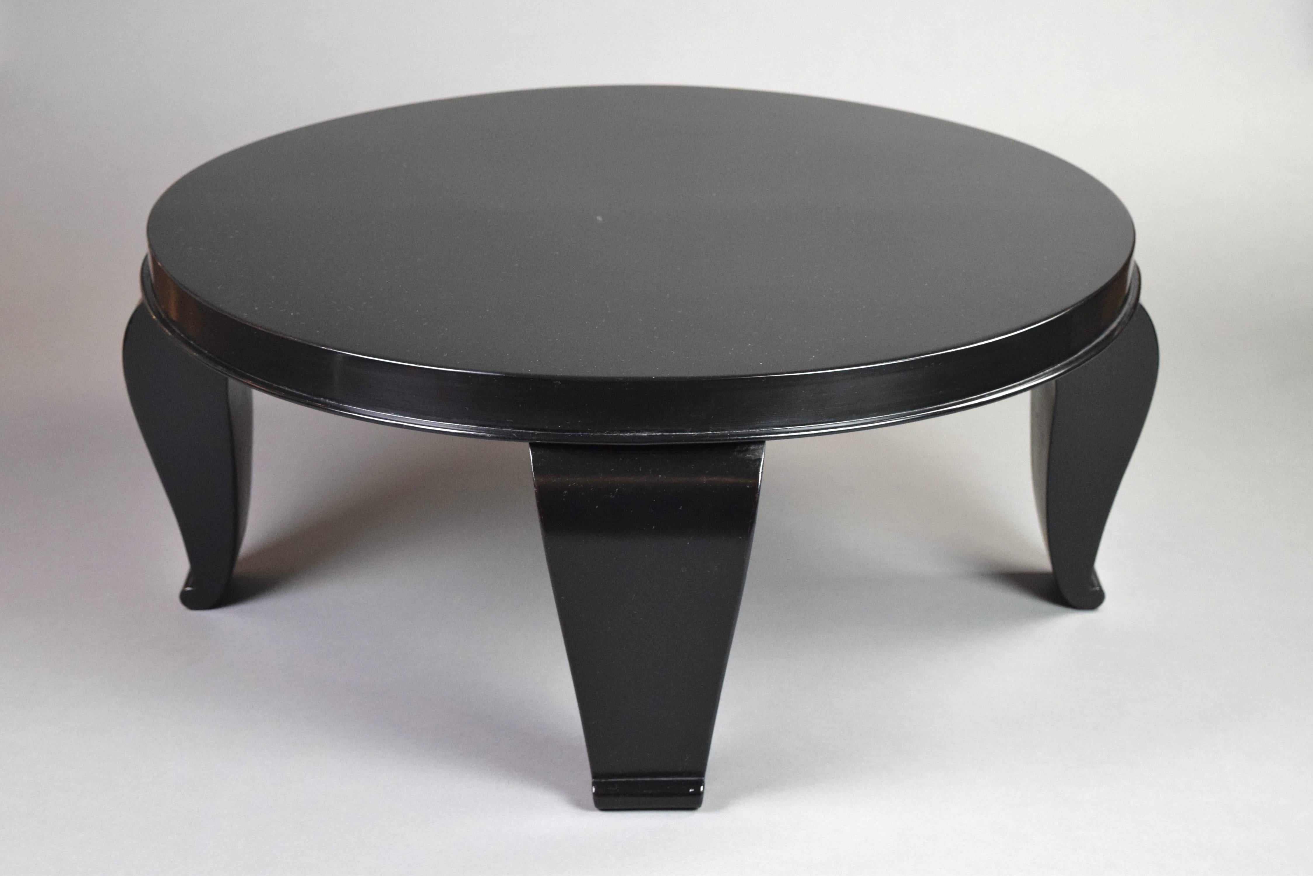 The Art Deco table has a circular top with a molded edge above four tapering curved legs with scroll feet.