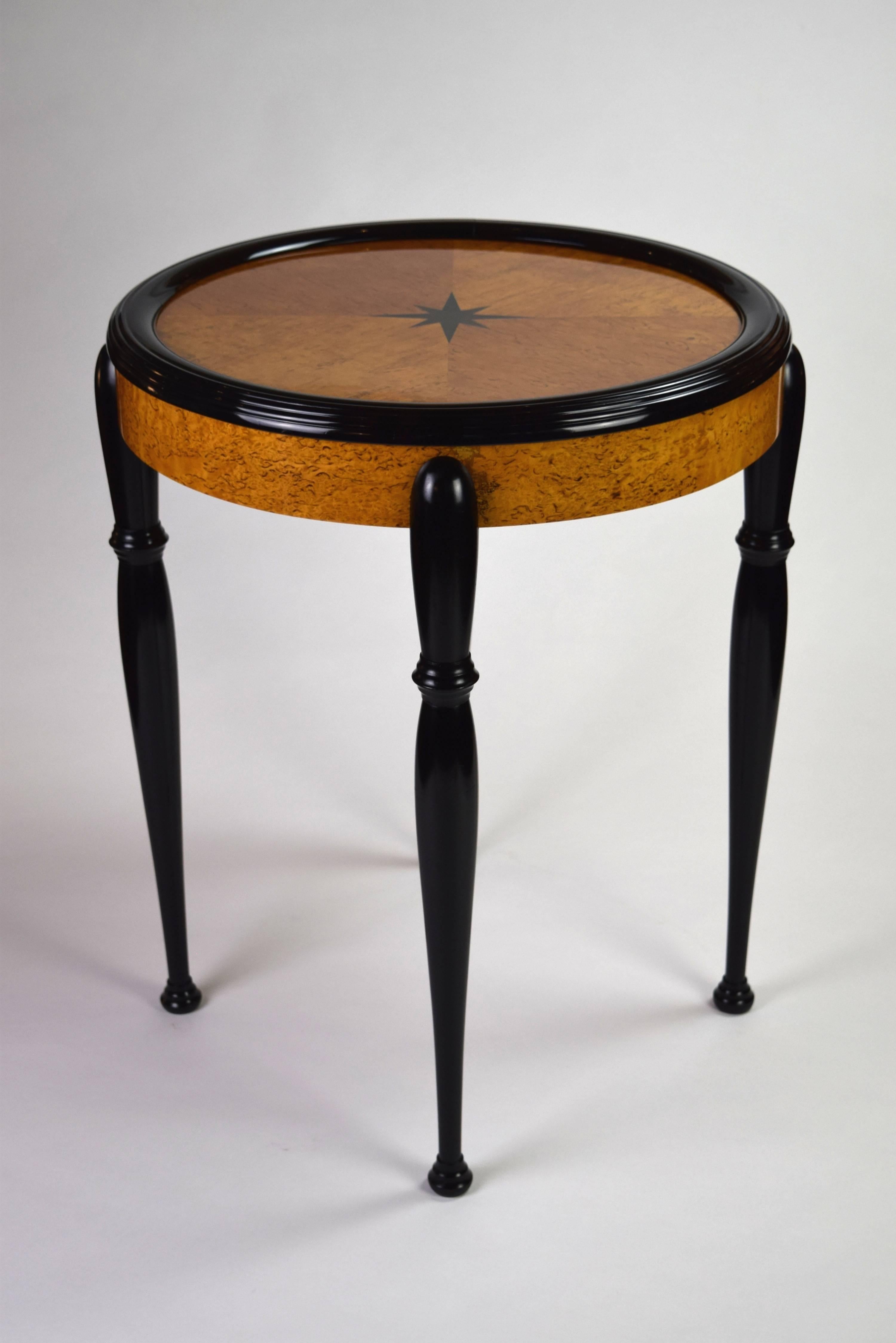 This elegant table features a circular parquetry top centered by a star and surrounded by a ripple-molded border, raised on slender tapering baluster legs.