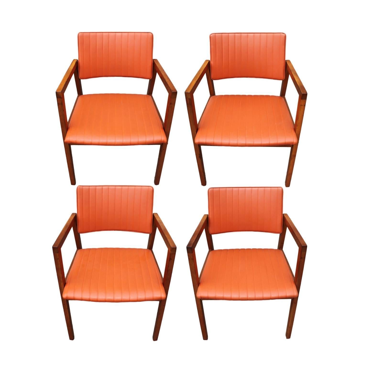 This great set of chairs features solid walnut construction with wafer-thin seat and backs upholstered in their original ribbed, salmon-orange vinyl. Despite their delicate lines, these chairs are actually very sturdy and quite comfortable. Dowel