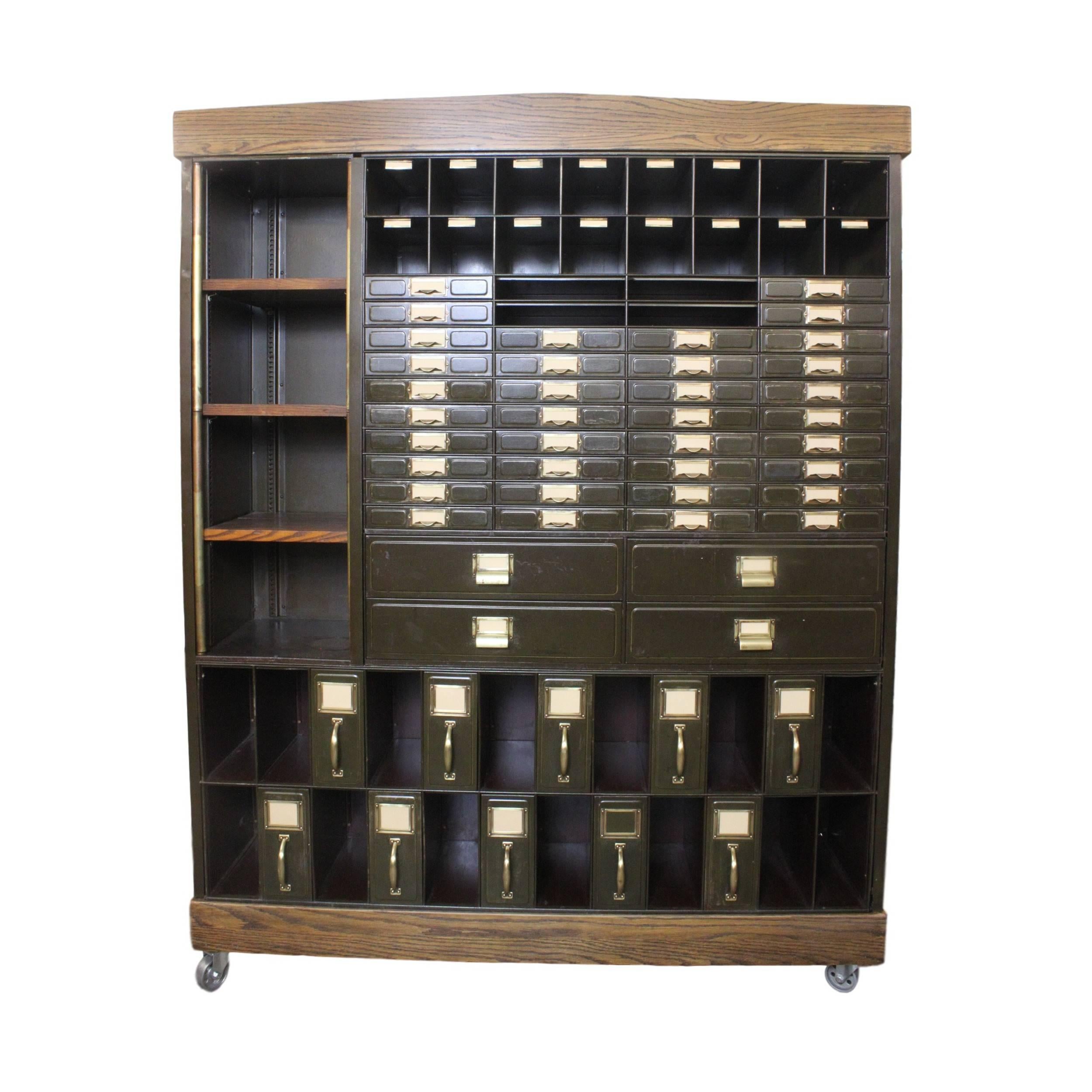This gorgeous 1920s courthouse cabinet has been customized in our workshop with solid oak base, adjustable shelves, and crown. Original green-painted steel cabinetry is complimented with original brass hardware or accents and original gold