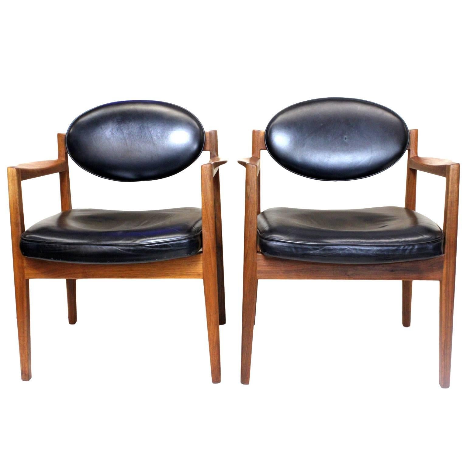 A fantastic set of Mid-Century Modern black leather and walnut club chairs by Danish American designer Jens Risom. From the early 1960s, these chairs are in excellent vintage condition. Chairs feature a gorgeous, sculptural design, beautifully