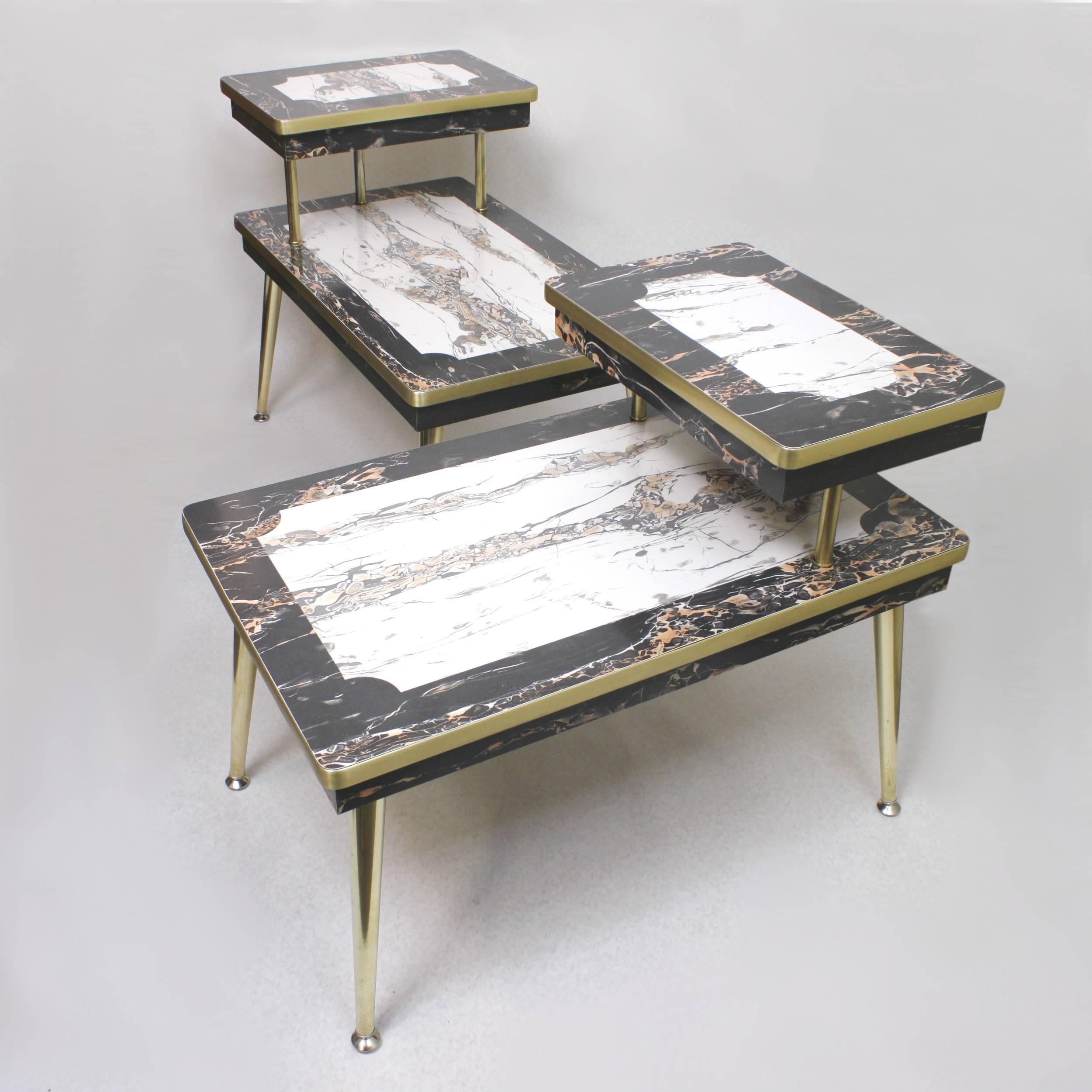 This crazy set of side tables features black and white faux-marble formica, brass legs, brass trim, brass risers and a unique two-tier design. These tables are built to a much higher standard of quality than most of tables of this type from this