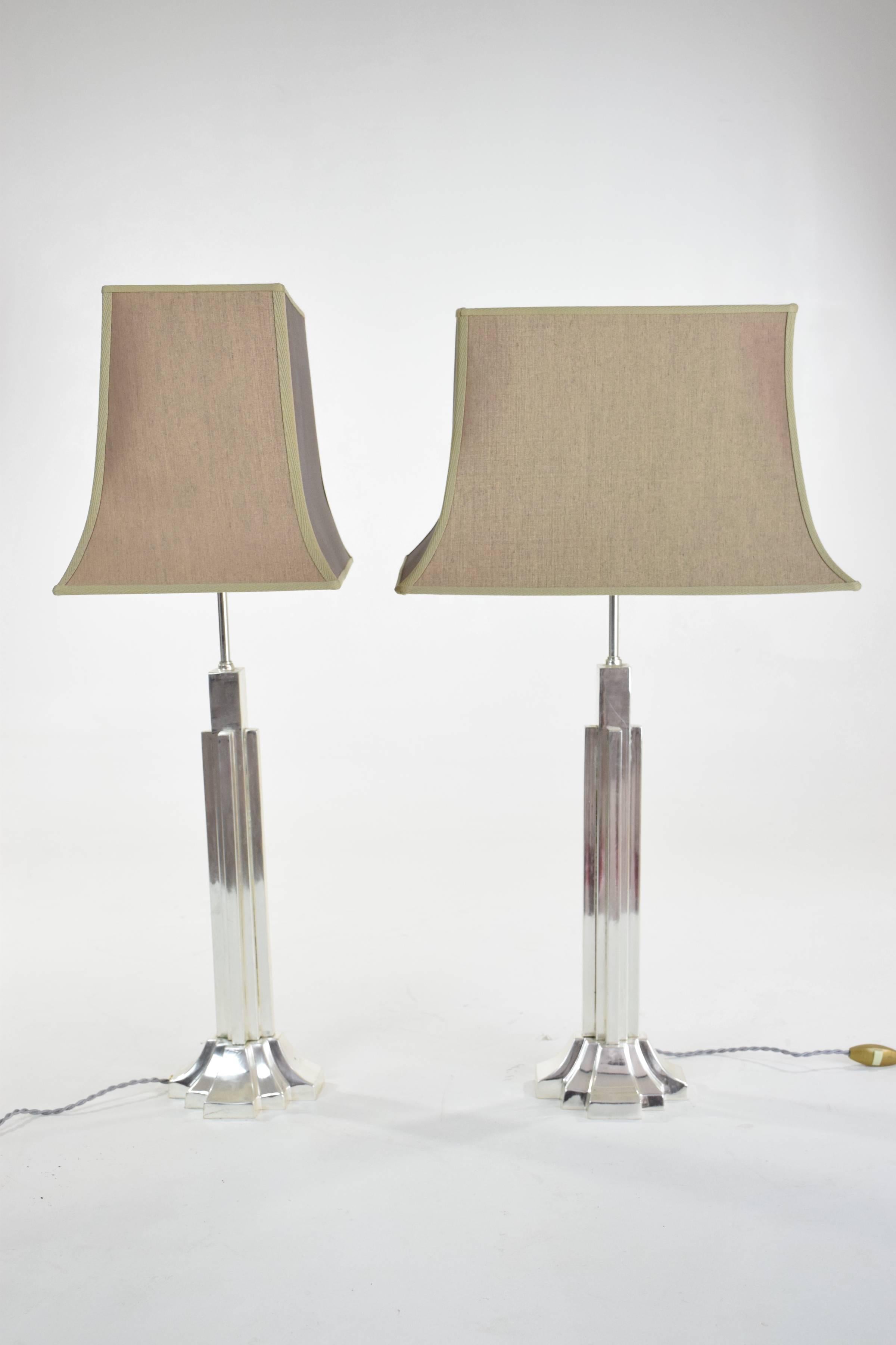 A graphic pair of French Art Deco table lamps of Asian influence with silvered brass structures produced around the 1930s. They have been fully restored with new shades, rewired and tested.
