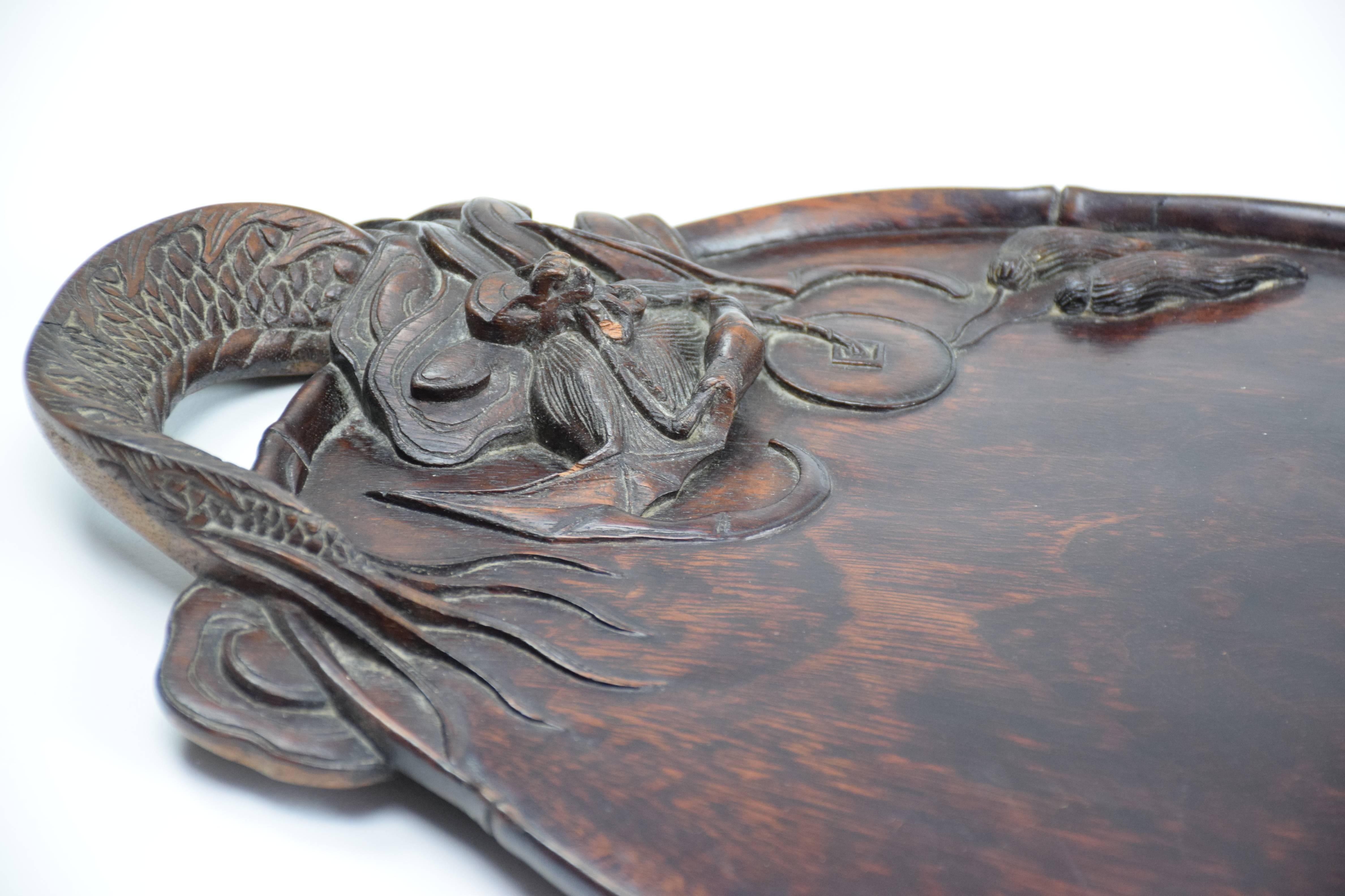 A fine antique Chinese two-handled serving tray carved from a single piece of lacquered softwood with intricate dragon shaped handles. Could also be used as a decorative wall piece.

China, end of 19th century.