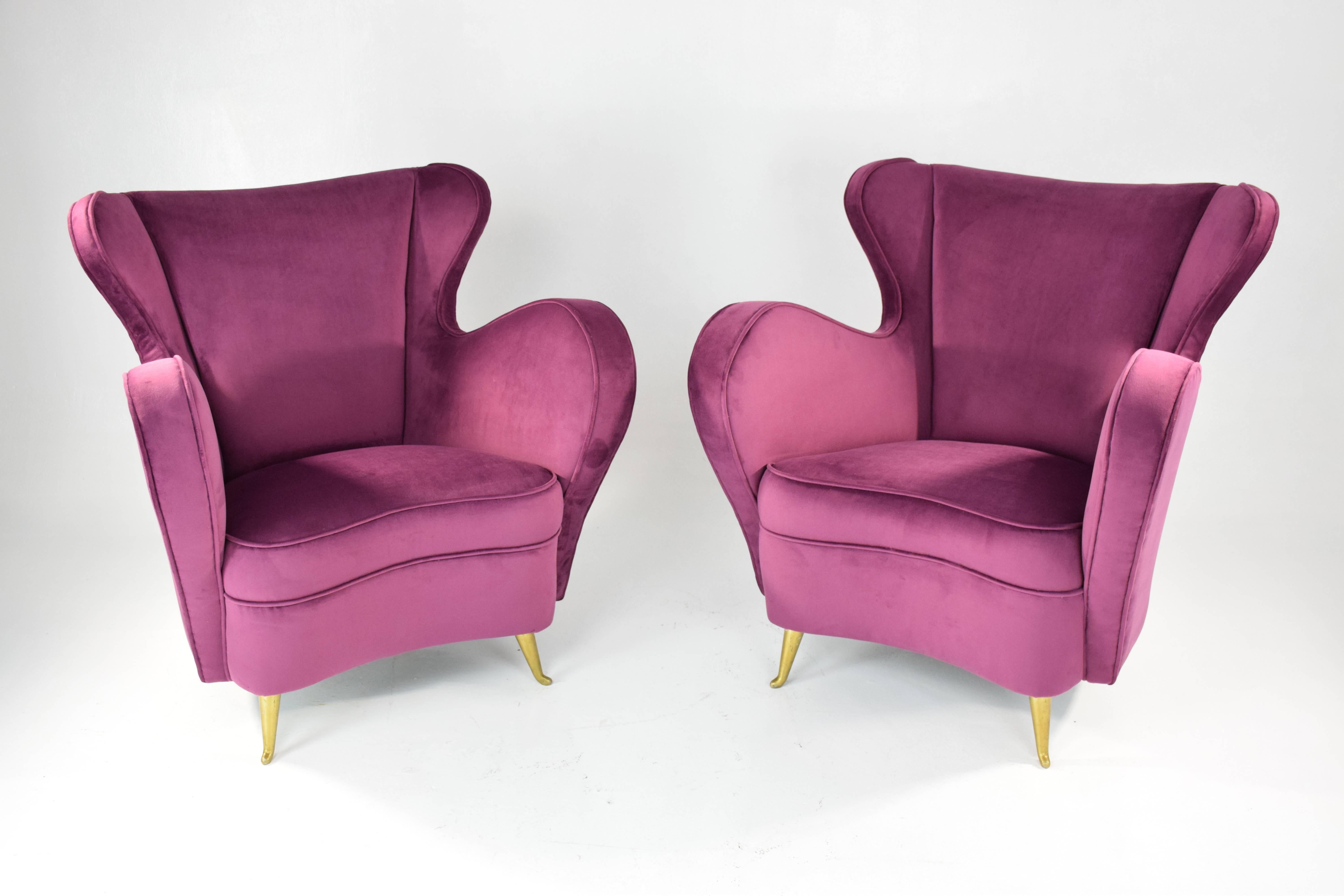 Pair of 20th-century vintage Italian curved club armchairs manufactured by ISA Bergamo. We have fully restored the seating in vibrant purple-pink velvet upholstery and brass polishing. 
Designed with the distinctive ISA upward curved feet.
Beautiful