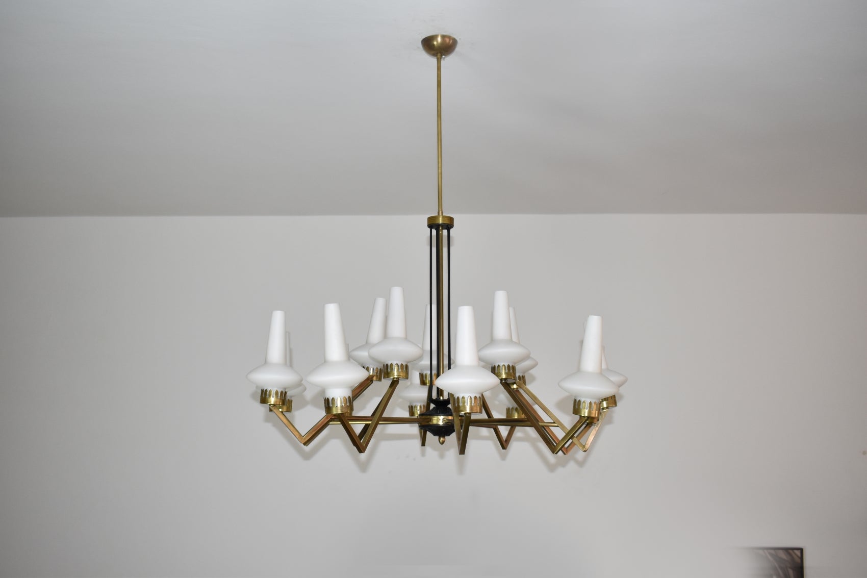 A spectacular Italian 15-arm chandelier from the 1950s attributed to Stilnovo designed with angular arms and original frosted glass shades. This collectable piece is highlighted by its black lacquered and sculpted details on the main structure. Each