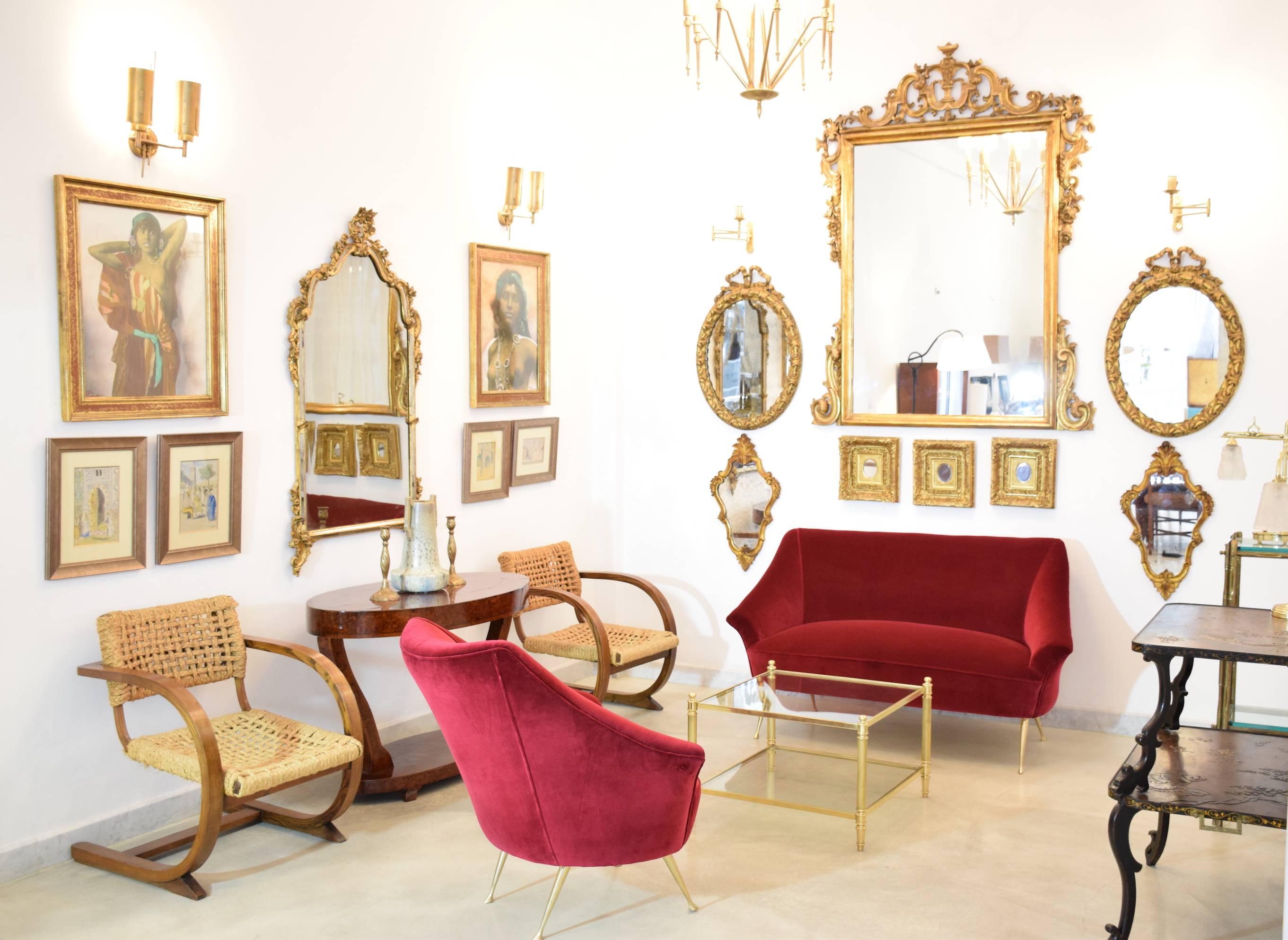A vibrant 1950's Italian brass-legged, curved two-seater sofa and armchair or lounge chair set. All meticulously fully restored by our artisans with one of the highest quality french upholstery makers, Lelièvre Paris, in a lush red velvet. 

The