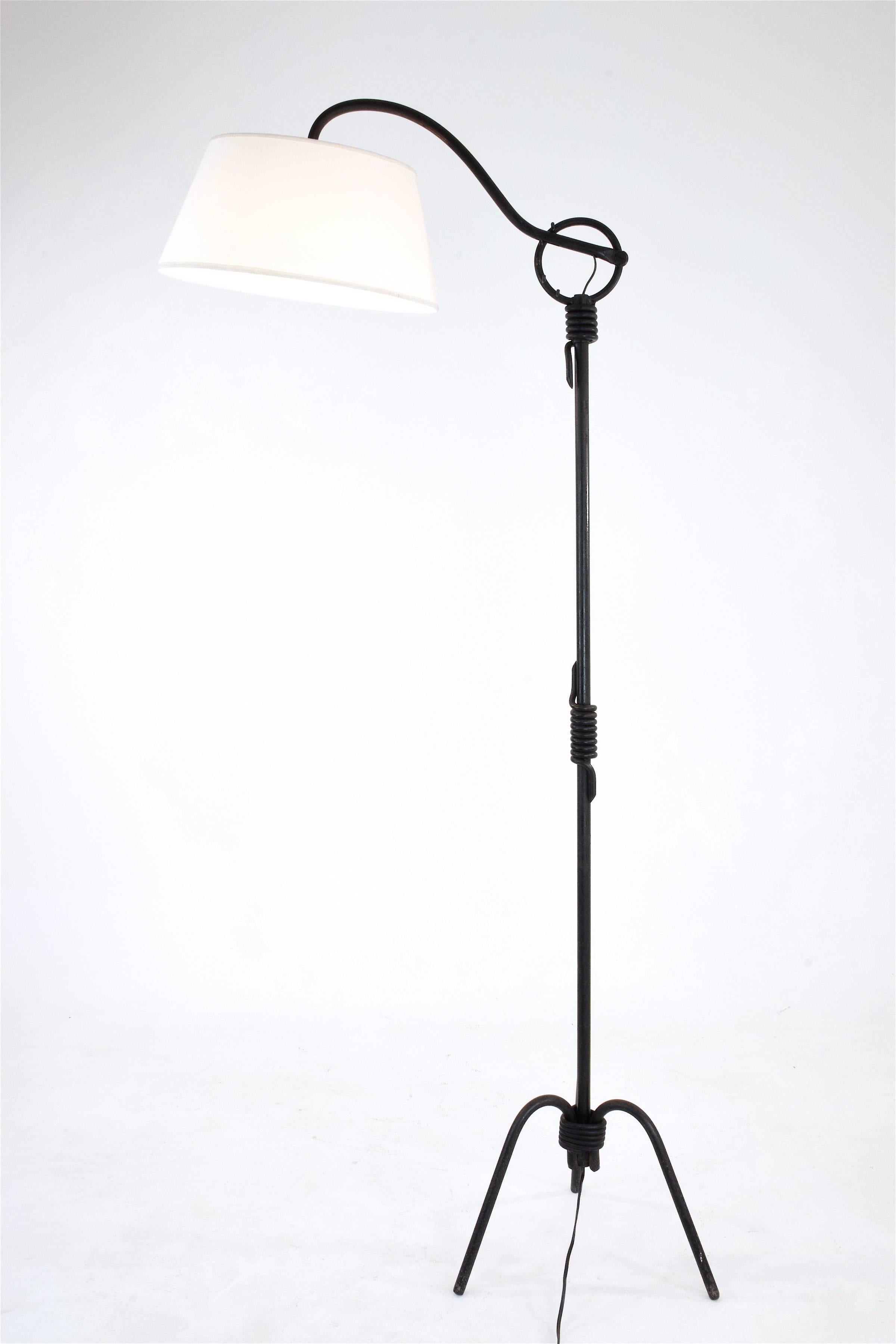 Historic 20th century vintage floor lamp by Jean Royère, France, circa 1940s composed of a wrought iron tripod base with beautiful patina and an adjustable lighting system. 

It has a new lampshade which matches its original style. 

Adjustable