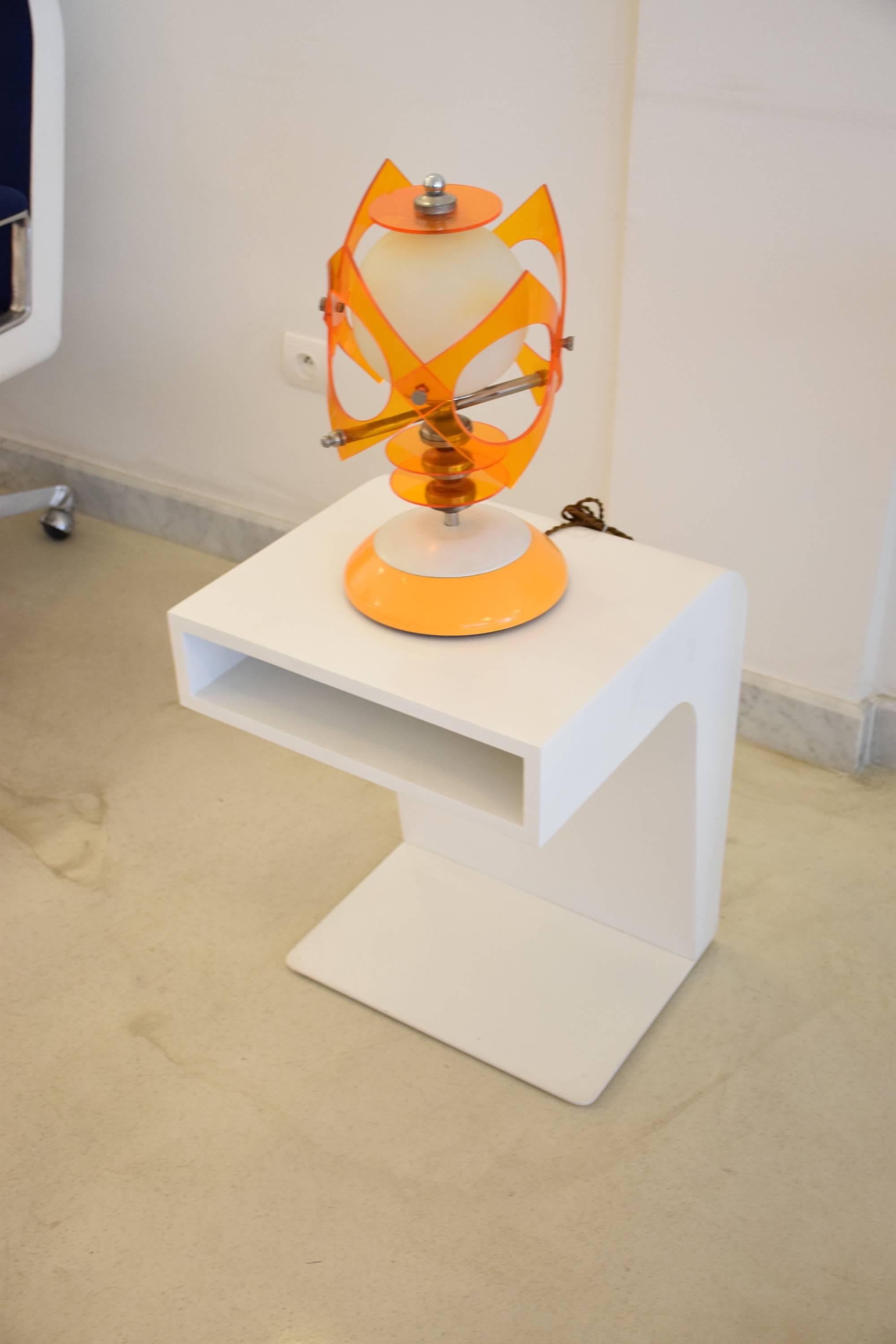 Unique vintage Mid-Century decorative table lamp composed of various materials: opal glass, orange Lucite and chrome, circa 1970s. The top design is held and detachable by an integrated magnet.