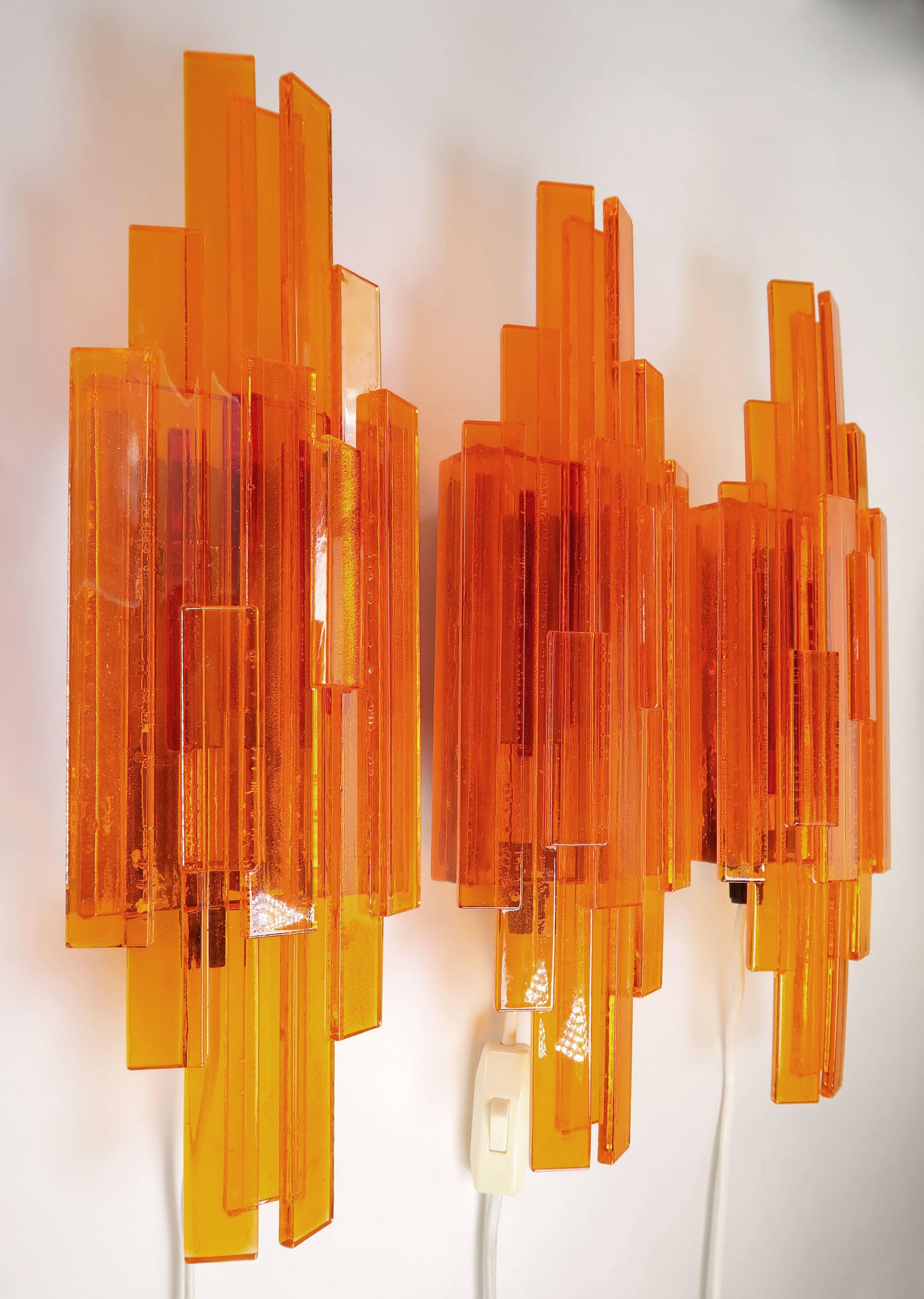 Set of three handmade Space Age wall lights of layered rectangular sticks of yellow and orange acrylic creating a sculptural triangular shape. Designed in 1975 by Danish flight engineer and designer Claus Bolby. Each item is handmade, and Bolby