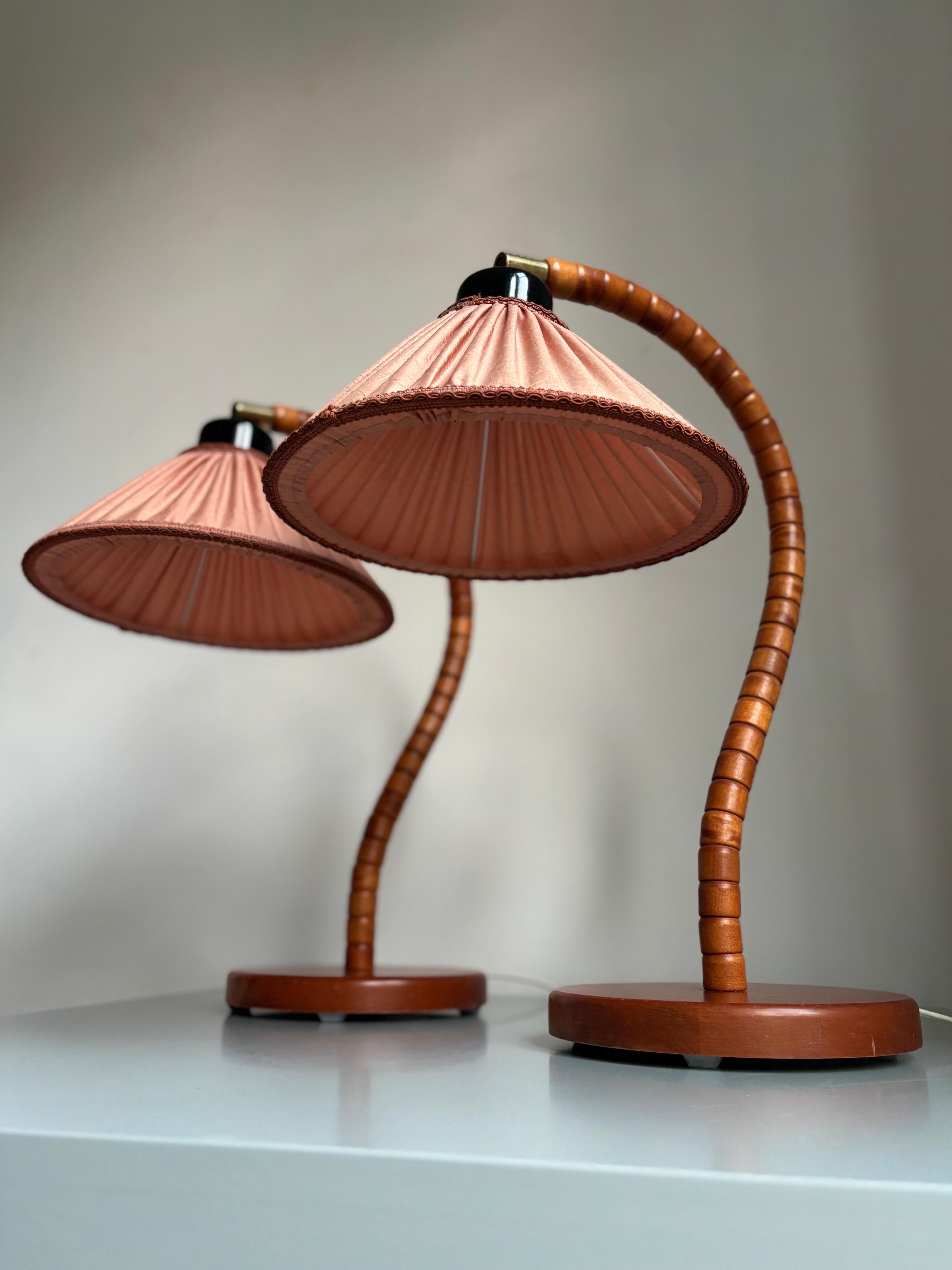 Coppia di lampade da tavolo moderne e scultoree prodotte da Markslöjd in Svezia negli anni '60. Le gradinate in legno di faggio massiccio a forma di collo di cigno poggiano su una solida base circolare su quattro piedi. Originali paralumi rosa