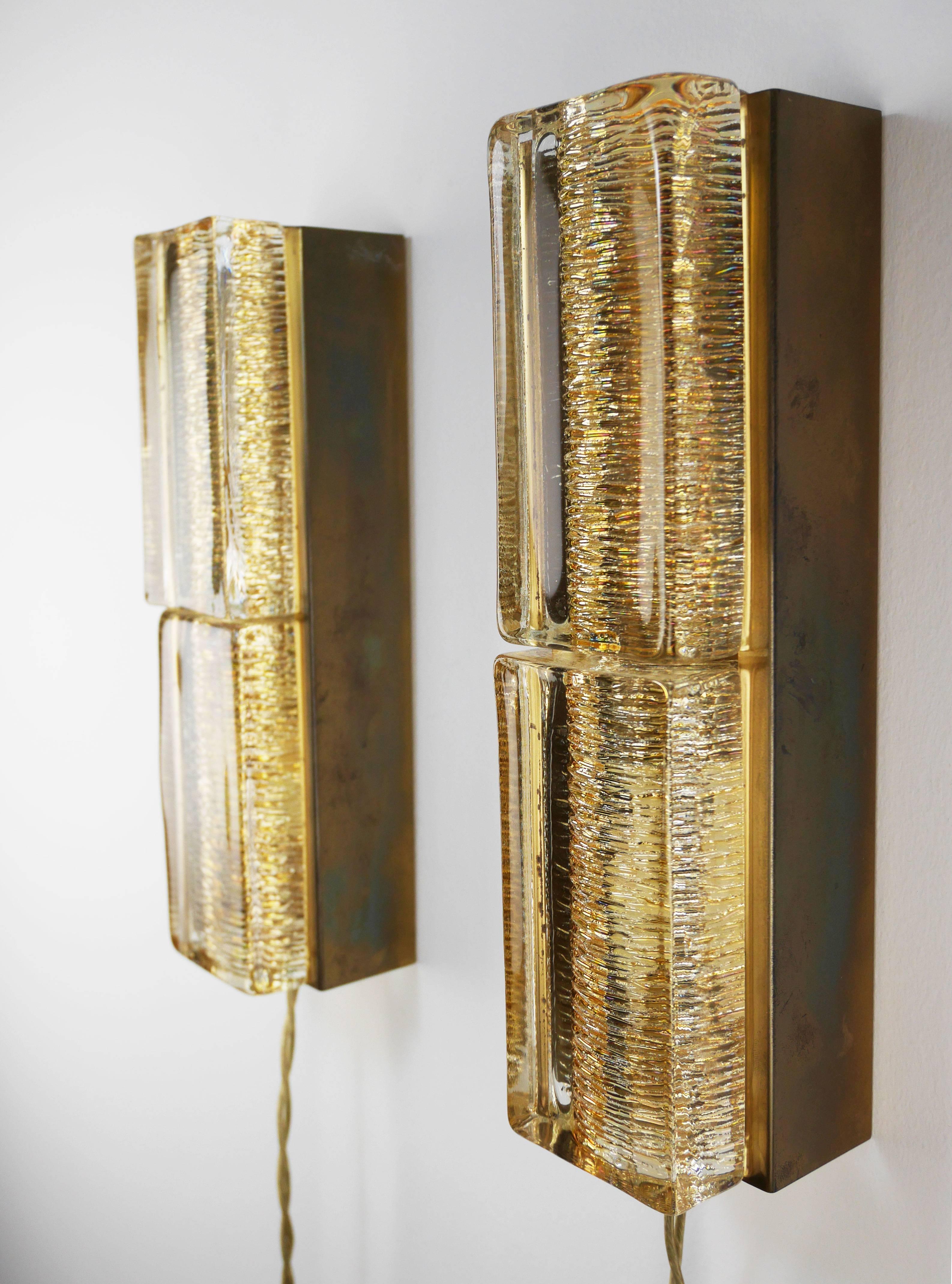 Rare pair of slender Danish modern double wall lights of solid golden glass on shiny brass mount. Produced by Danish Vitrika possibly with Orrefors glass in the 1960s.