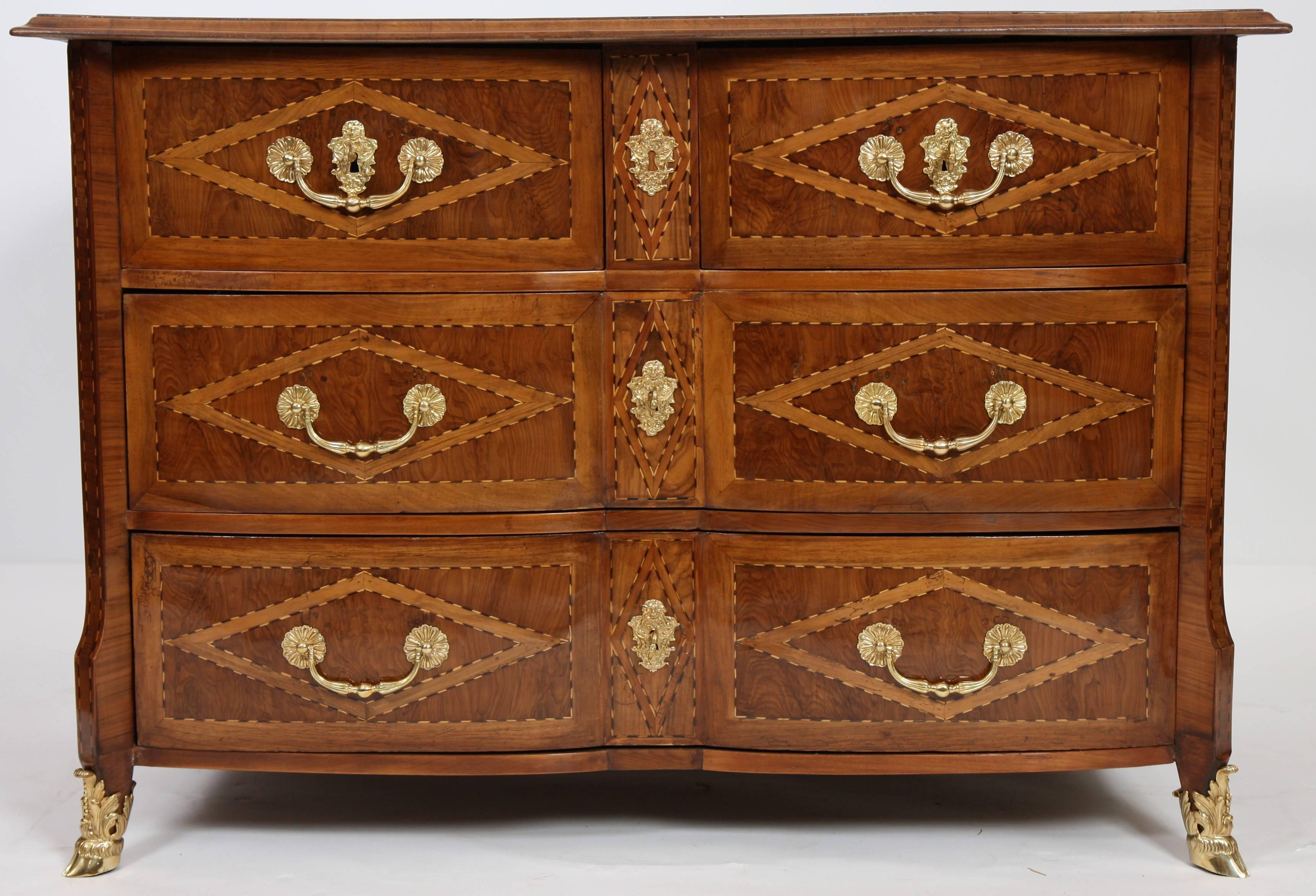 Pretty olive wood marquetry with geometric decoration. It opens with four front drawers of which two in the upper part. Crossbow facade, inlaid wood tops, flat sides.
Pull handles, keyholes and crowbars in chiseled and gilded bronze.
Restoration