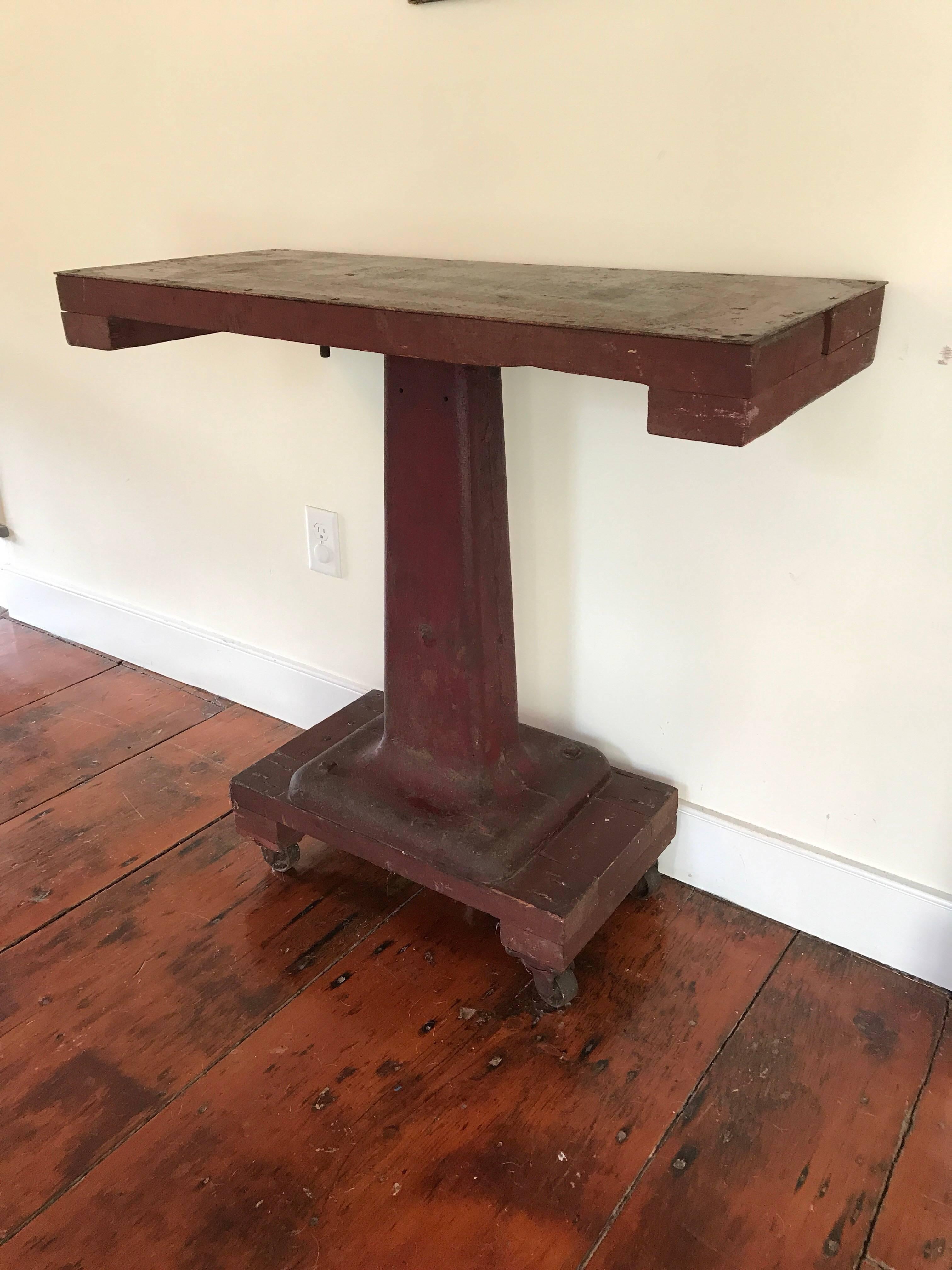 Une table console industrielle en acier et en bois de style Empire avec une fabuleuse finition rouge délavée. Base en acier lourd avec roues et plateau en acier relié par du bois. Fabriqué artisanalement au milieu du 20e siècle à partir de matériaux