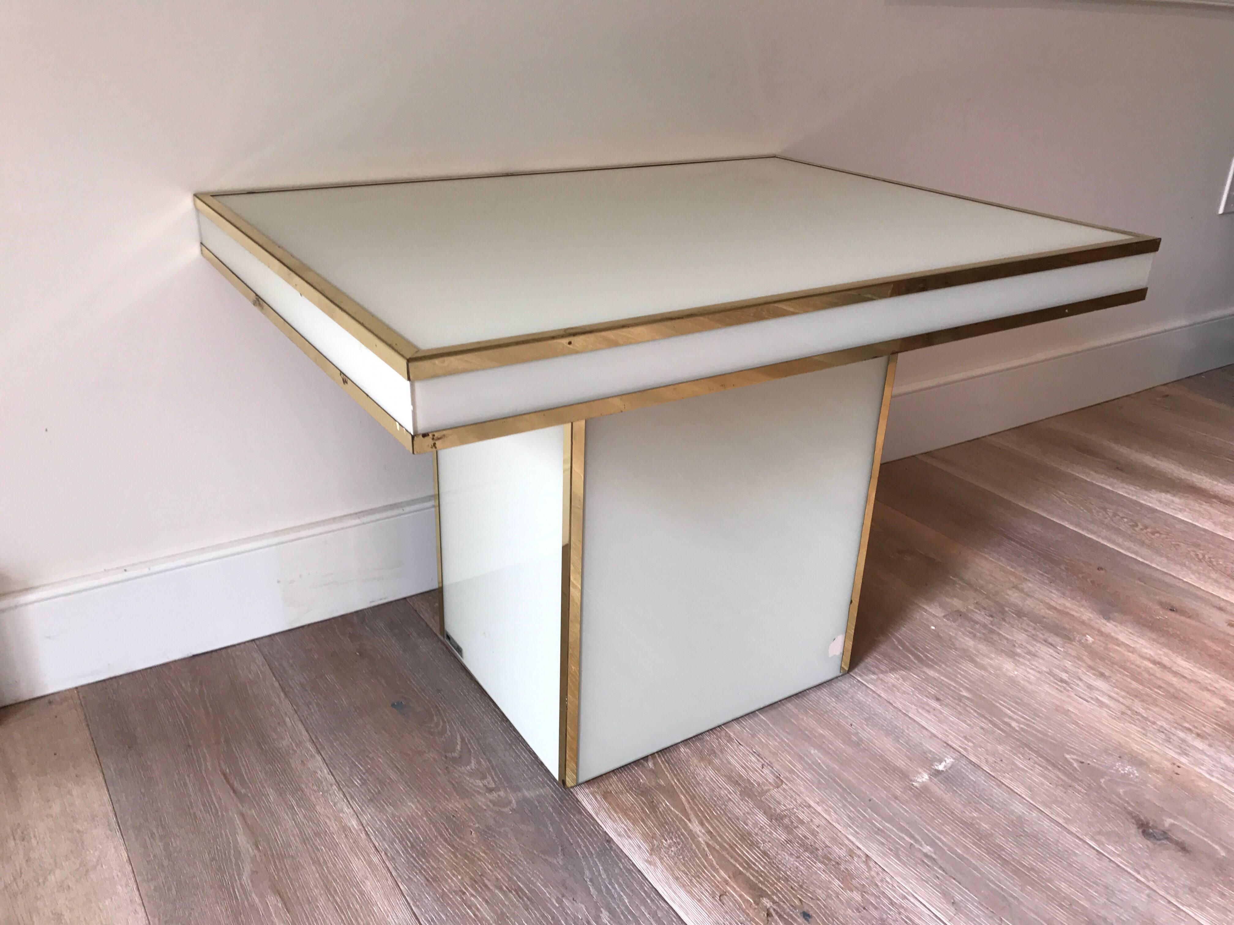 A rectangular low table by Rougier. White glass surround and brass seams.