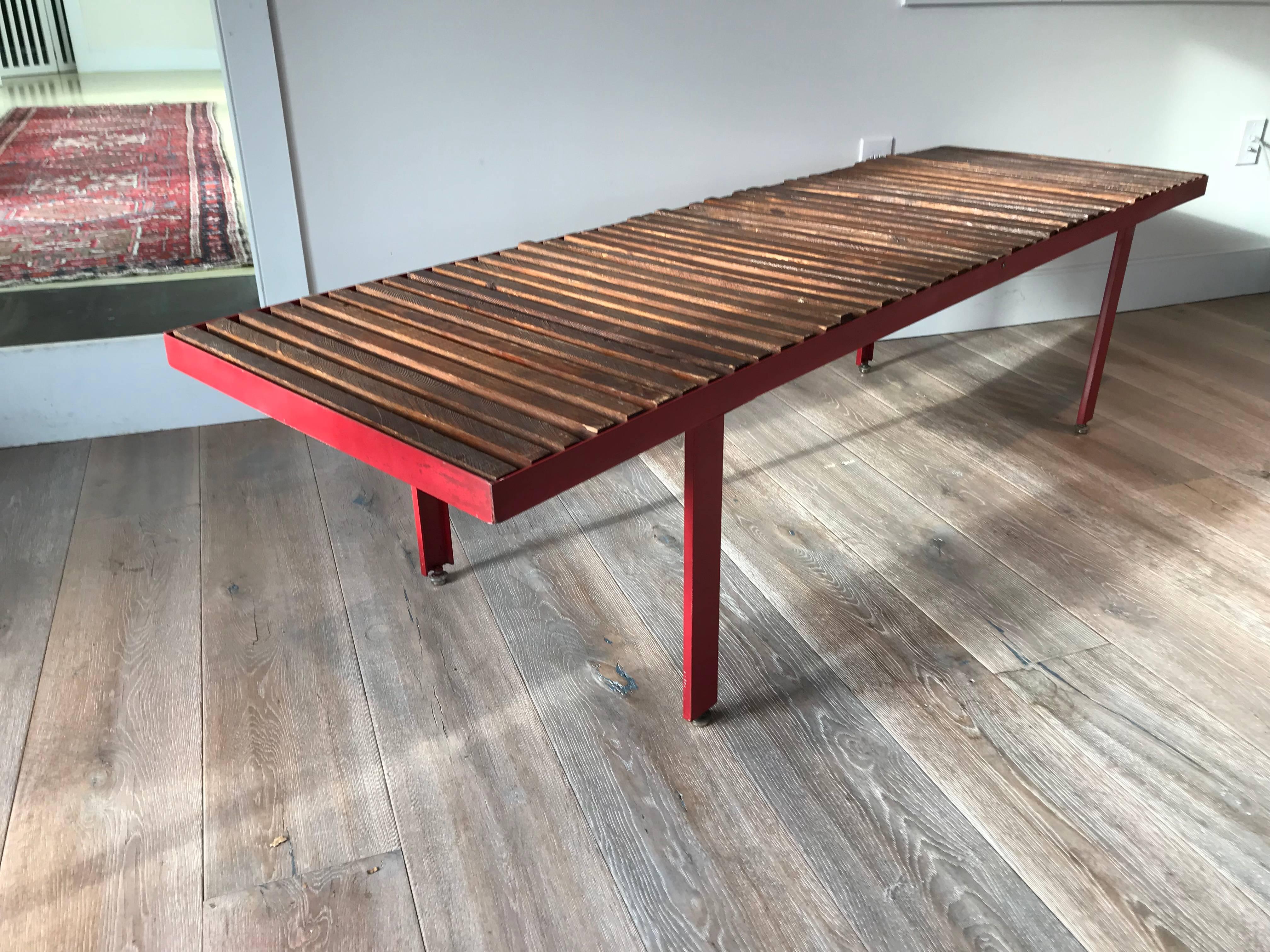 Interesting mid-20th century red lacquered metal bench or daybed with stained slatted wood seat. In the manner of Jean Prouve. Spring loaded feet make this a sturdy and level piece.