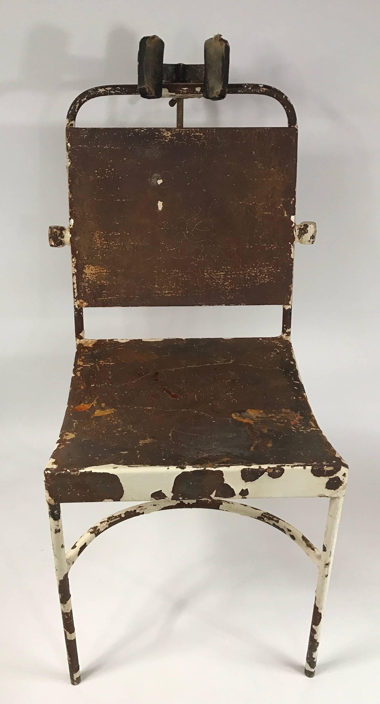Interesting antique medical chair. Original untouched condition showing iron frame through distressed white paint. The headrest adjusts vertically.