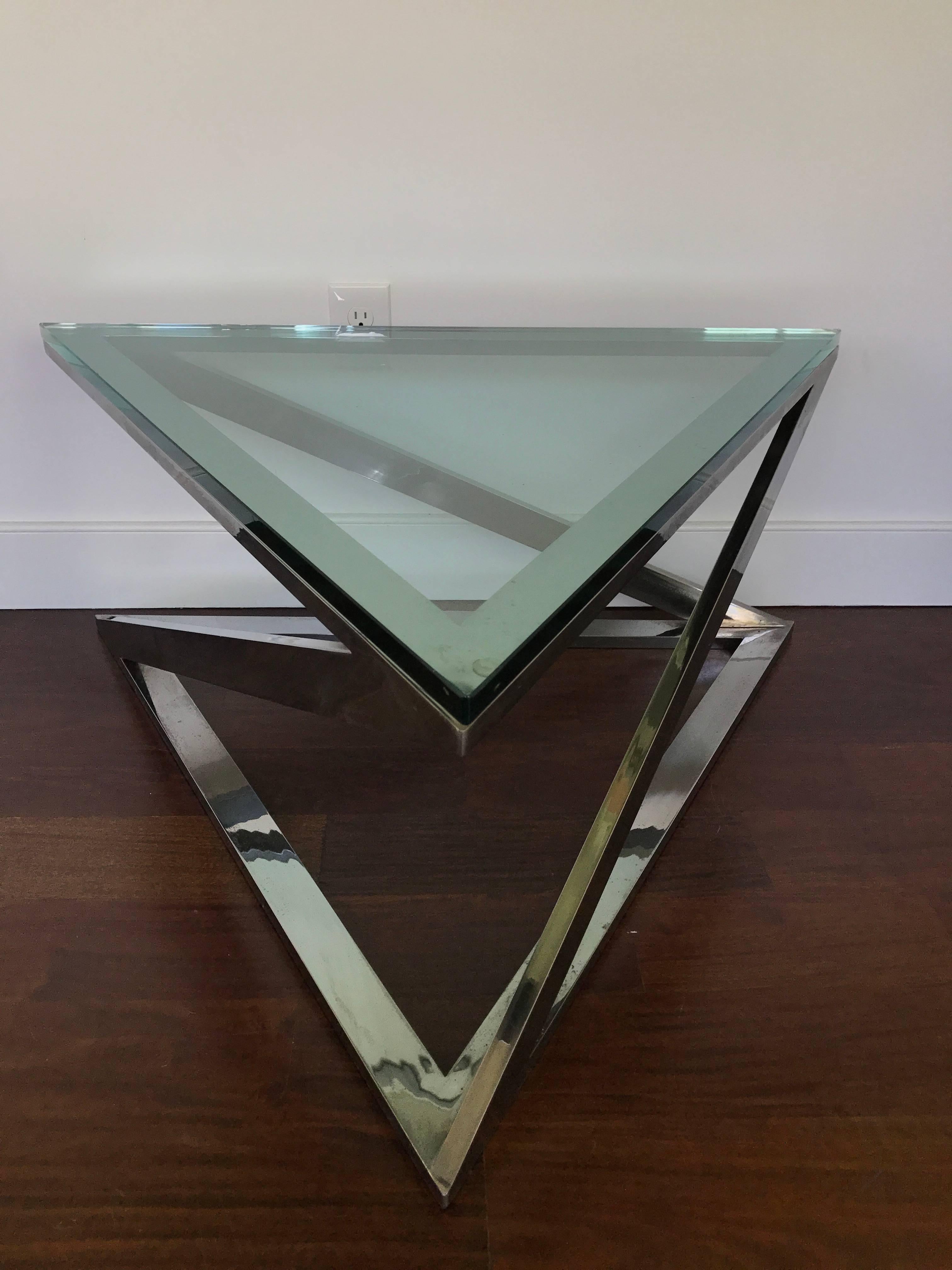 Architectural triangular form chrome cocktail table with thick glass top.