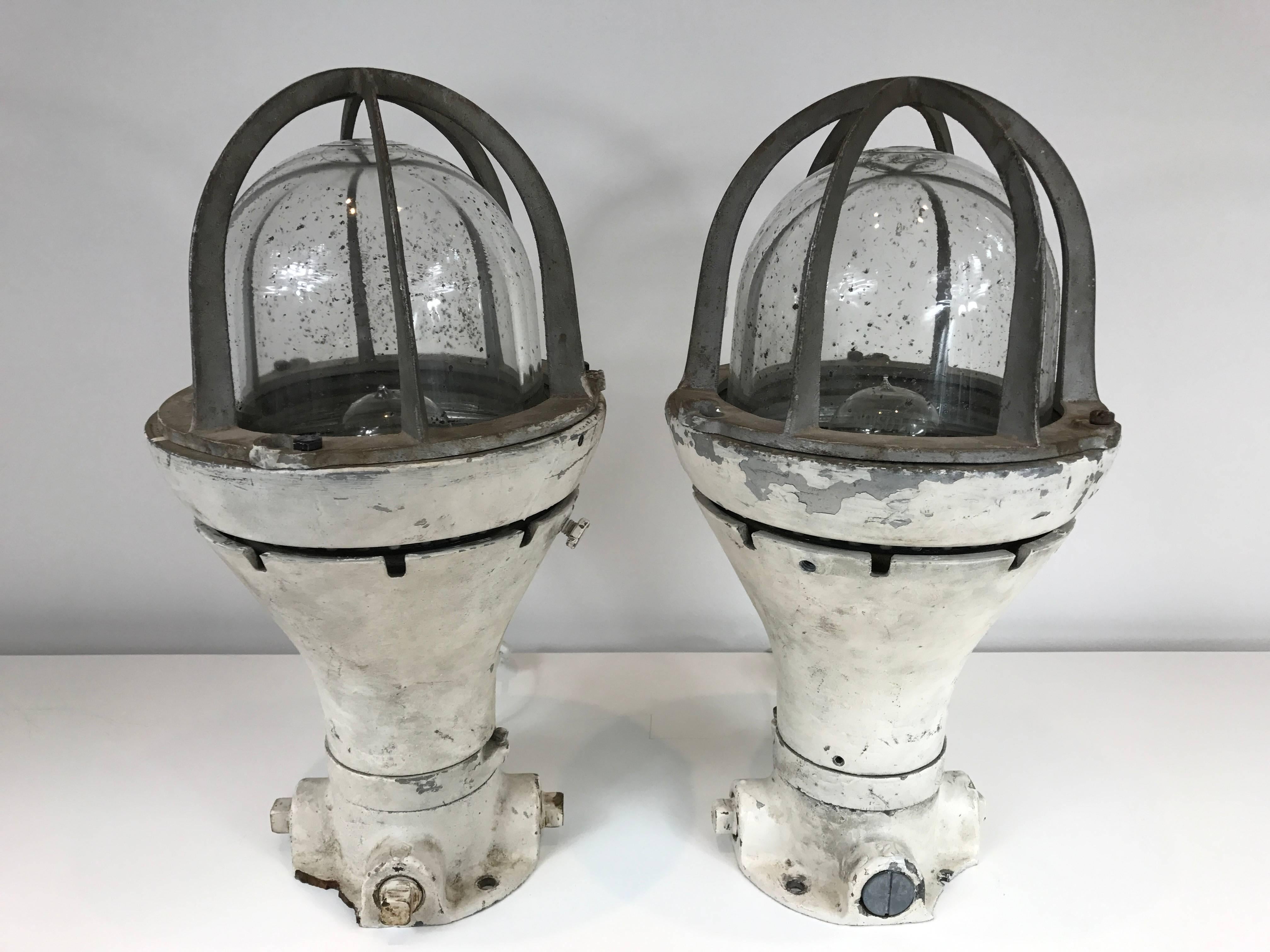 Pair of vintage ship lanterns with blast proof lights now wired as table lamps. Heavy steel body with glass globe covers. Rewired.