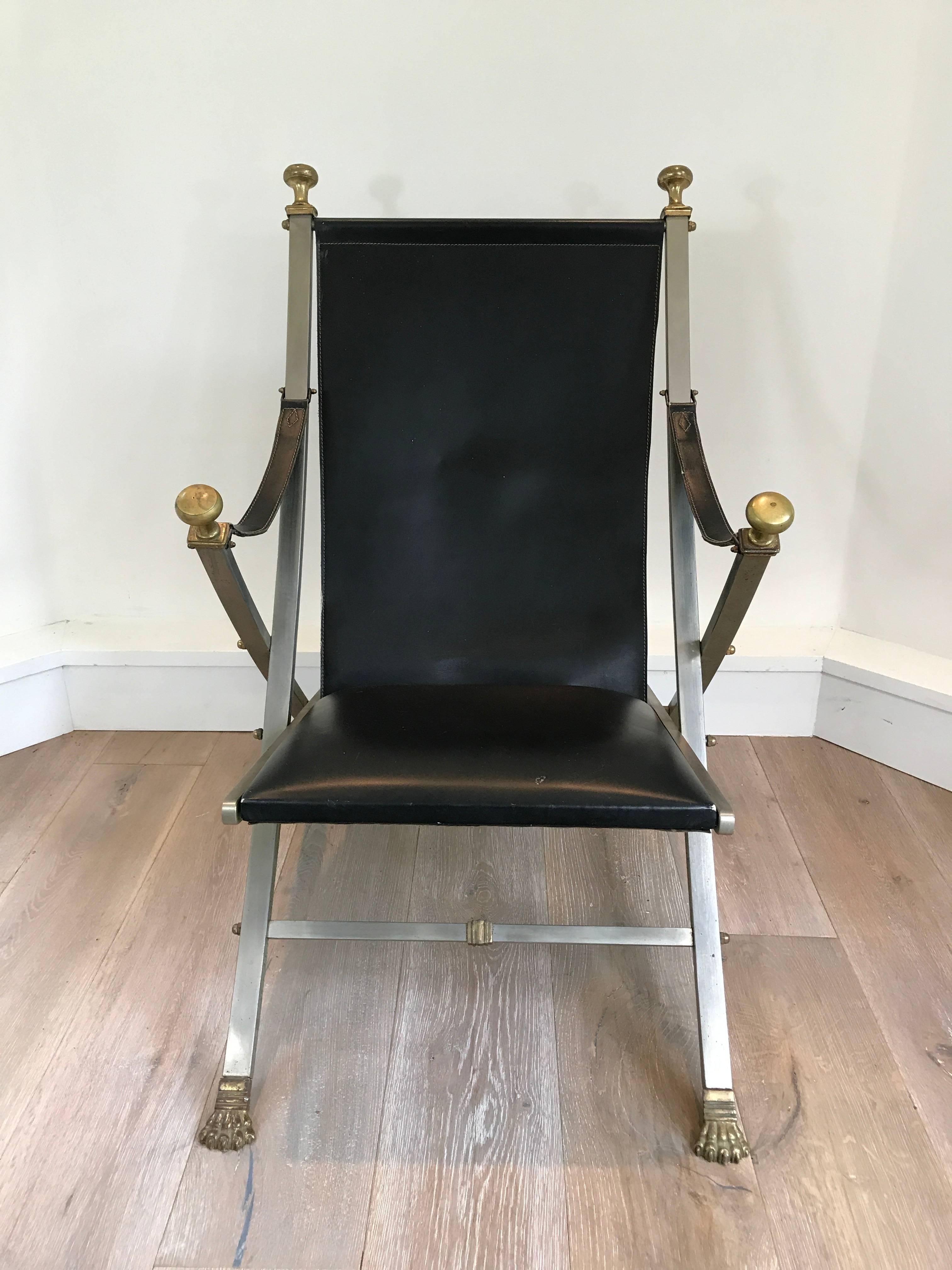 Pair of Maison Jansen campaign armchairs. Black leather seat with steel and brass accented frame. Wonderful patina to metal. Solid and heavy construction.