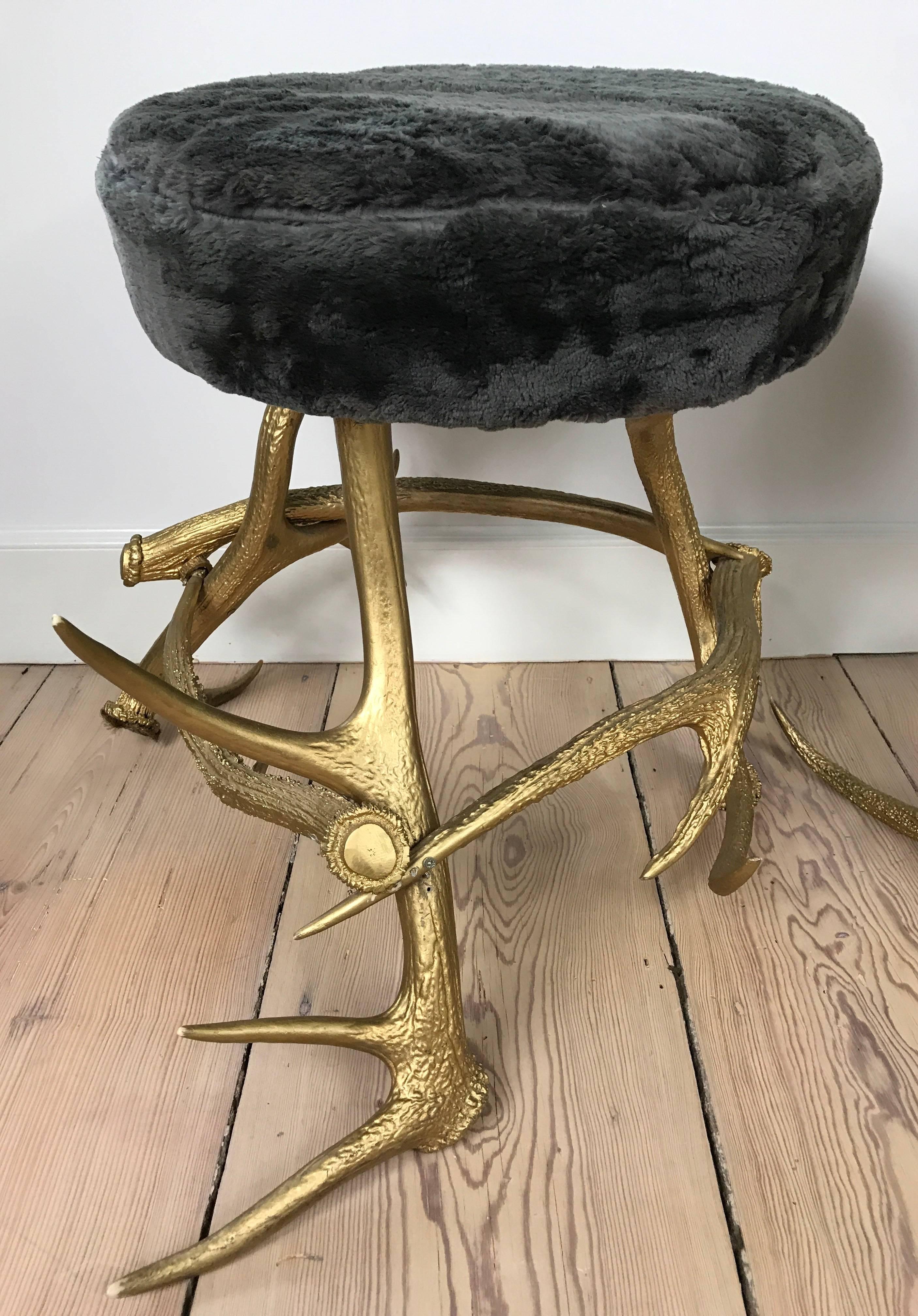 A pair of custom-made antler stools with gold painted finish and soft grey beaver fur upholstery.