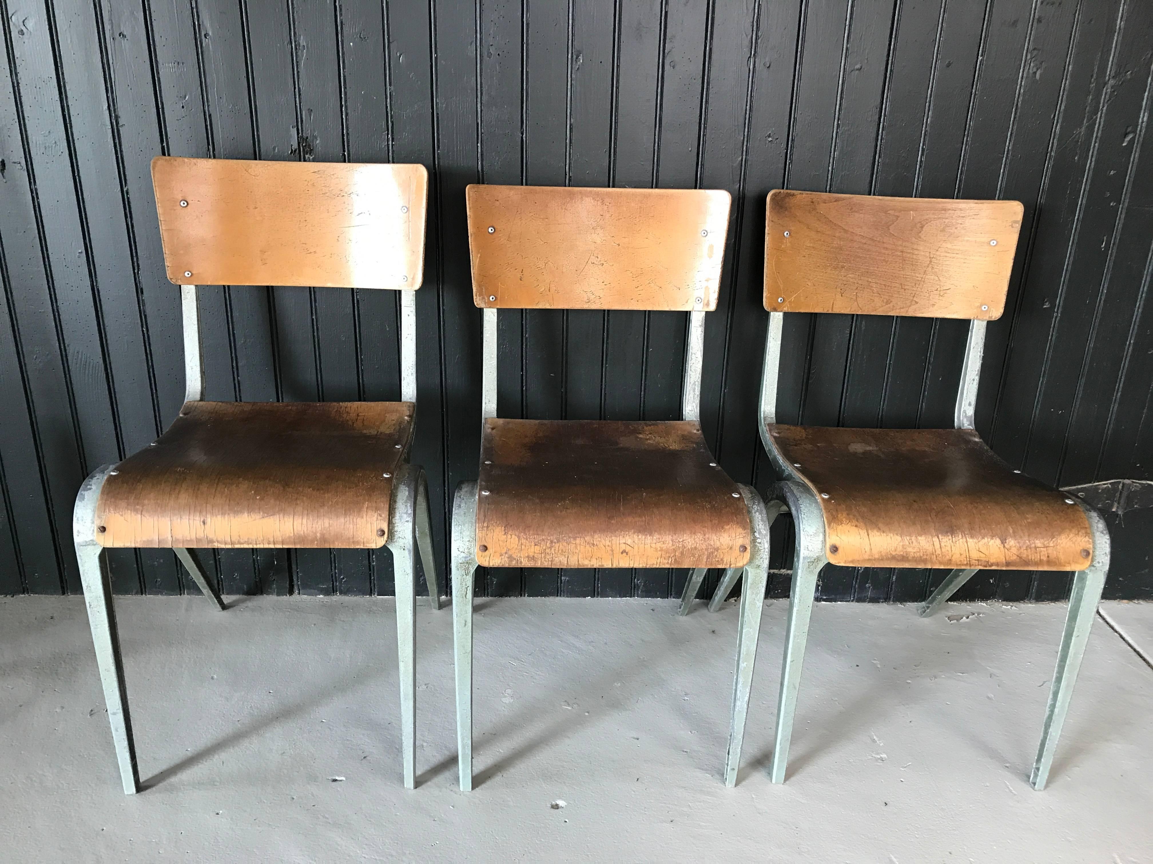 A set of three Industrial stacking chairs. Metal frame with architectural curved legs and bentwood seat and backrest. All show original patina consistent with age and use. Sold individually. One has a slightly higher profile.