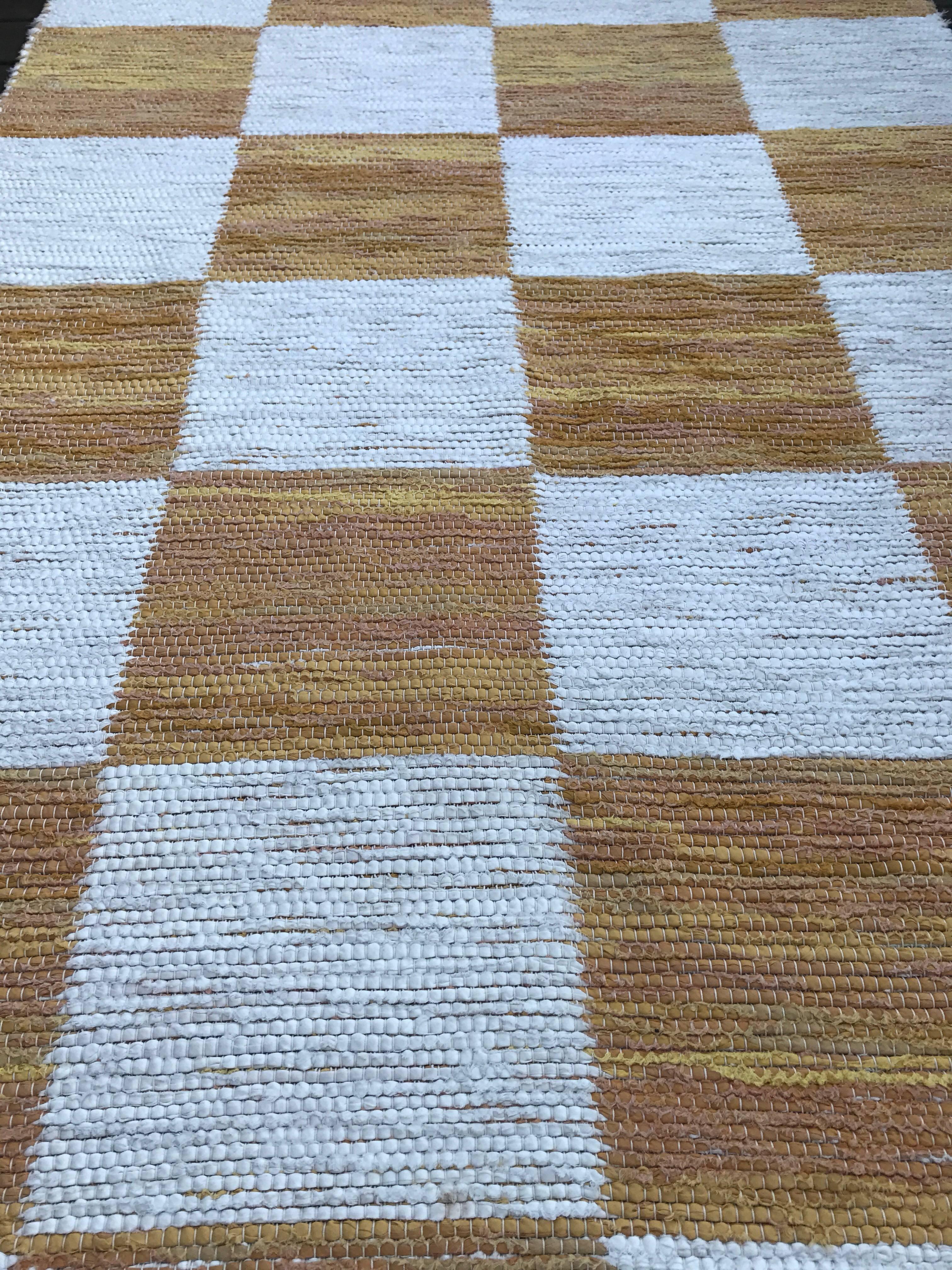 A very simple but beautiful white and yellow square flat-weave cotton carpet made and sold by Svenskt Tenn. It measures 232cm long and 125cm wide.