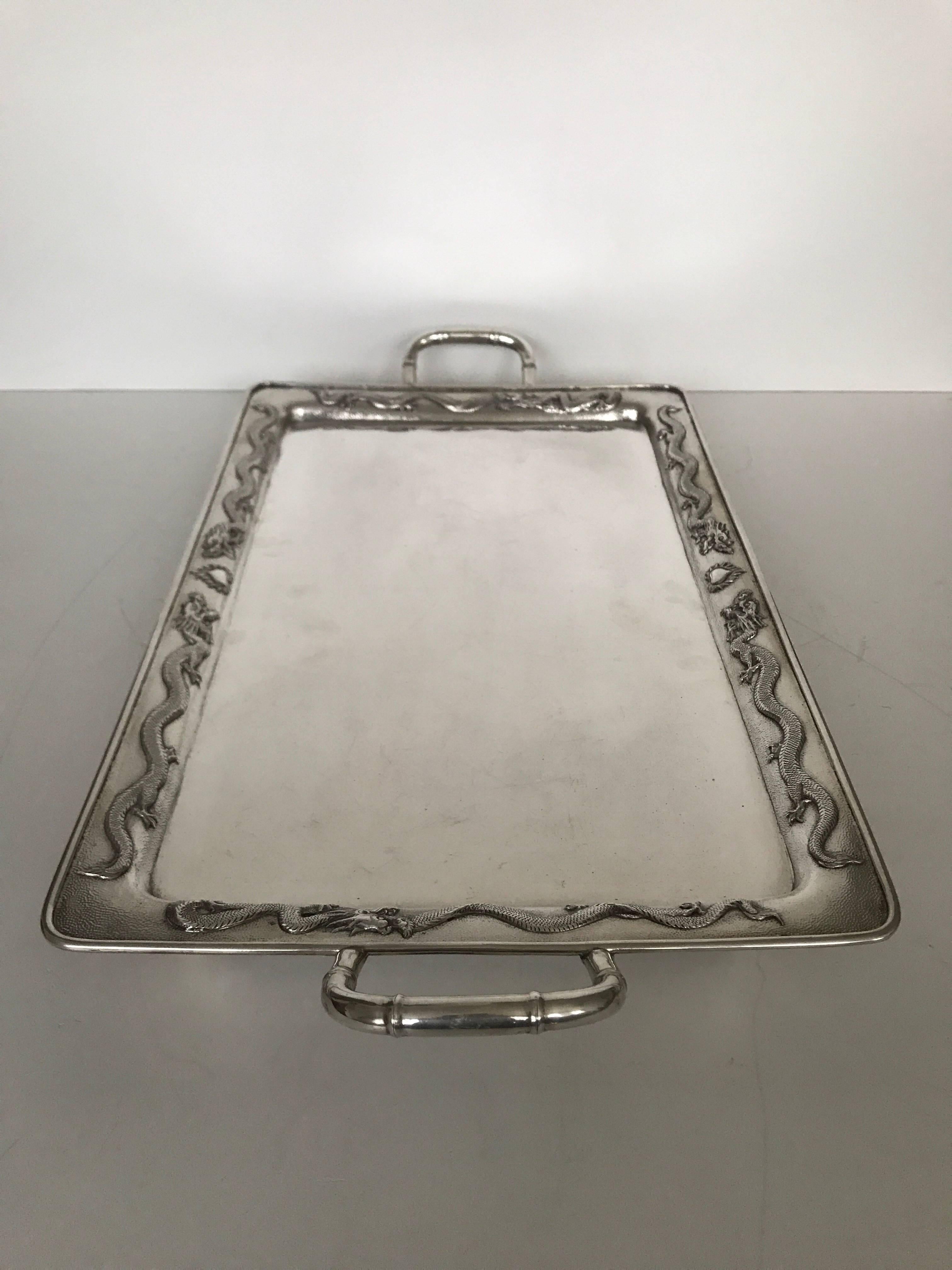 Massive Chinese Dragon Export Silver Tray Made by Luen Hing. A Fantastic Export silver tray with 6 dragons chasing the flaming pearl along the border of the tray. The handles are made like bamboo and the tray has four corner feet that it stand on.