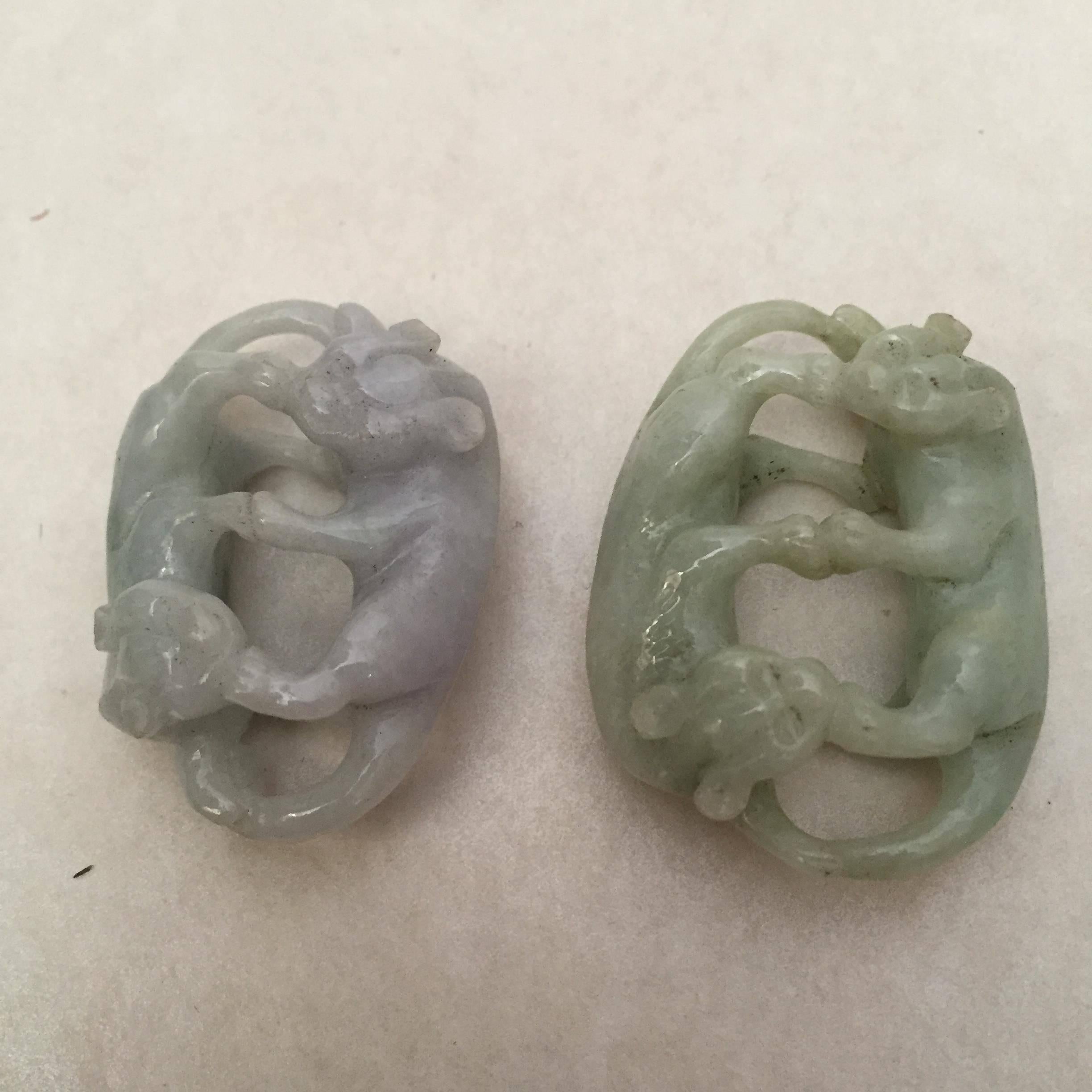A pair of beautifully carved Chinese lavender and green jade double cat pendants. The pendants measure 4 cm in length and 3 cm in width. They are most likely made in the early mid-20th century and they are in a very nice condition without any flaws.