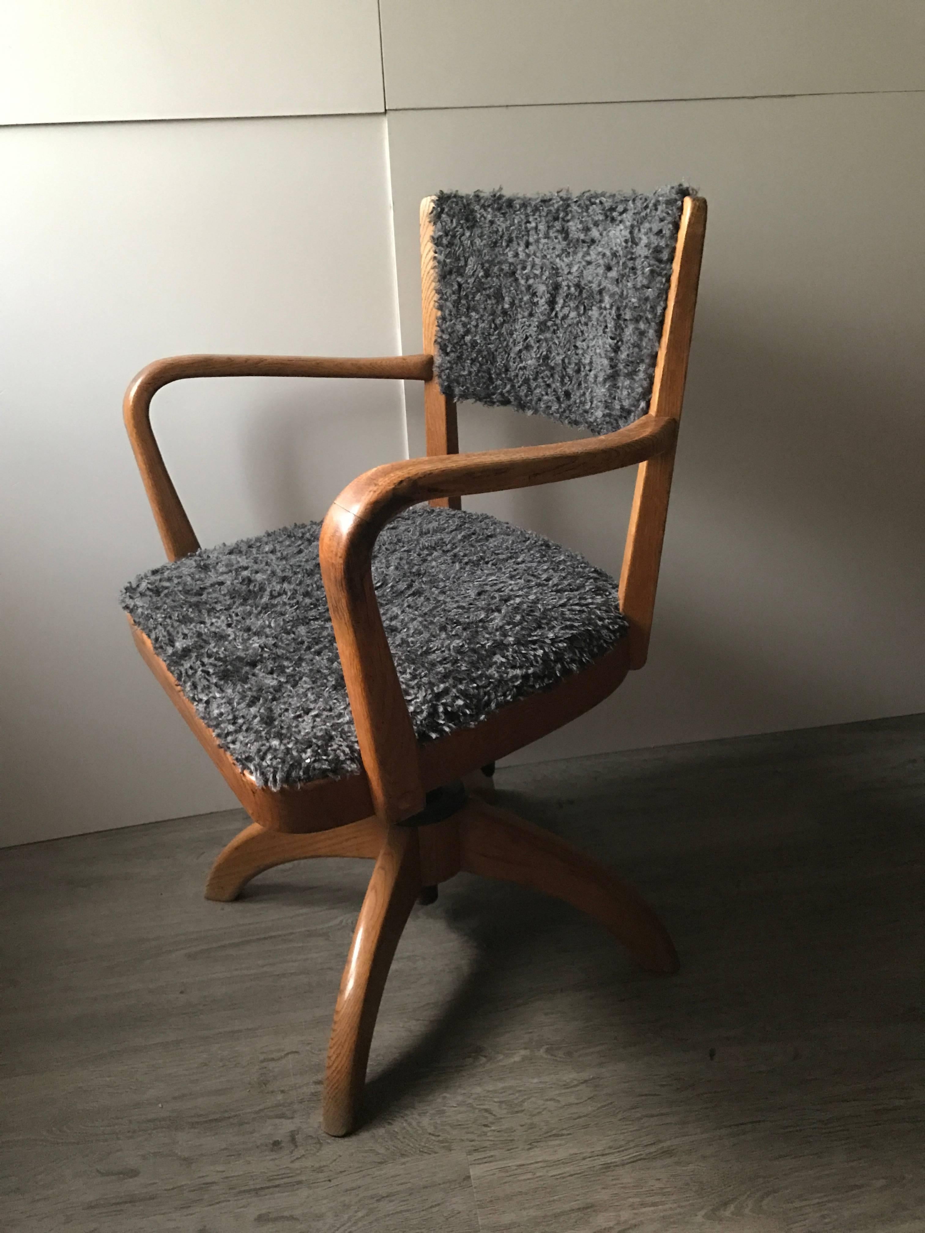 A beautifully shaped Swedish Art Deco oak office chair with faux sheep fur covering both the seat and the back. It has a tilting function and can also be adjusted in height. The chair is in a fantastic condition and has not any damages or