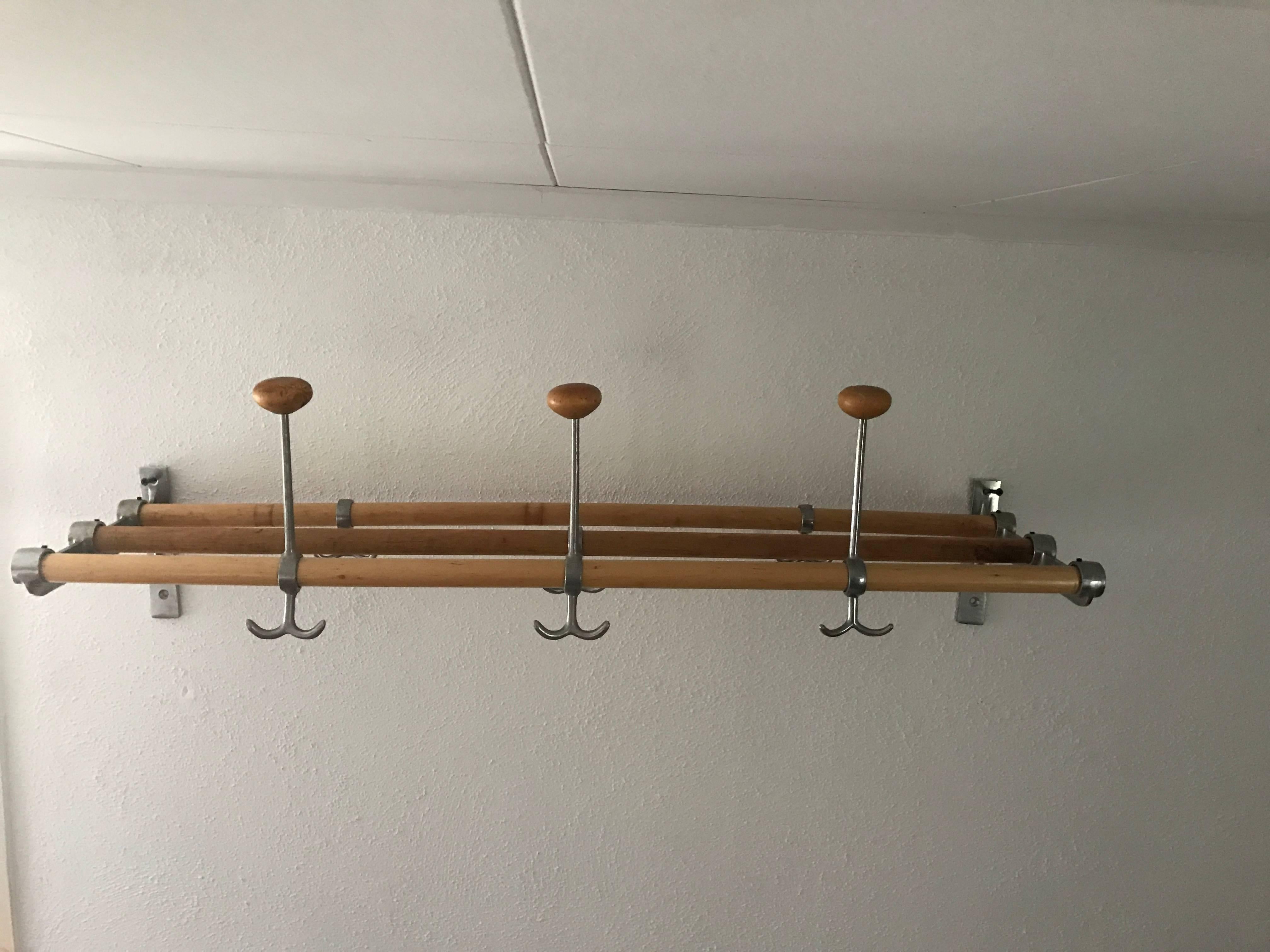 Mid-20th century Swedish Functionalistic coat and hat rack wall mount made of wood and brushed aluminum. This very nice rack is an icon of Swedish functionalism, with three hat pins with wooden finial. It is in a very nice condition, everything is