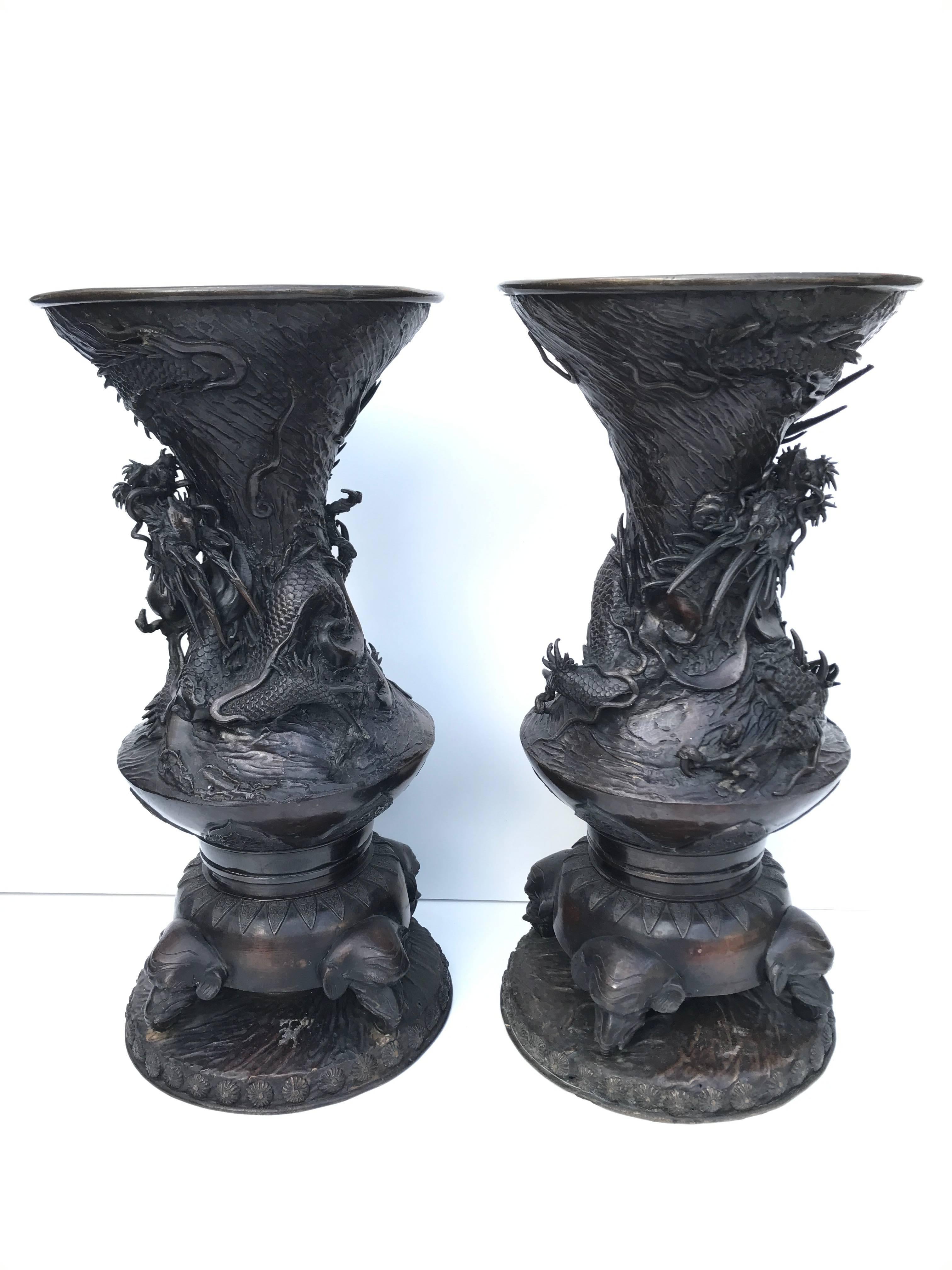 Large Japanese Meiji style period bronze dragon urns.
Beautifully casted bronze urns with a majestic dragon going in and coming out from the urn, chasing the flaming pearl. This pair is just absolutely magnificent and the details are amazing,