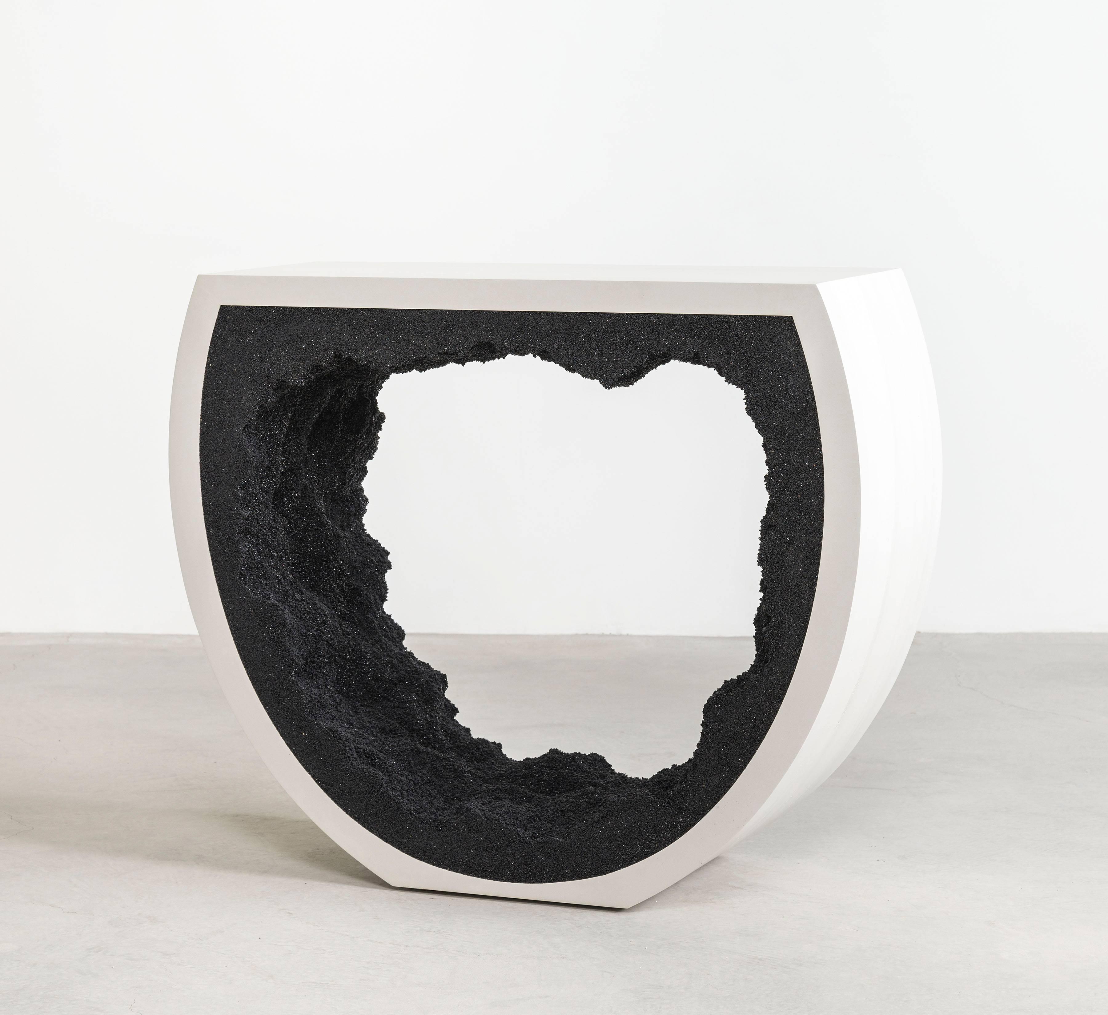Composed from a combination of materials, the semicircle console consists of a hand-dyed cement exterior and a silica interior. Packed by hand within the smooth white cement, the black silica forms an organic texture to contrast the strong structure.
