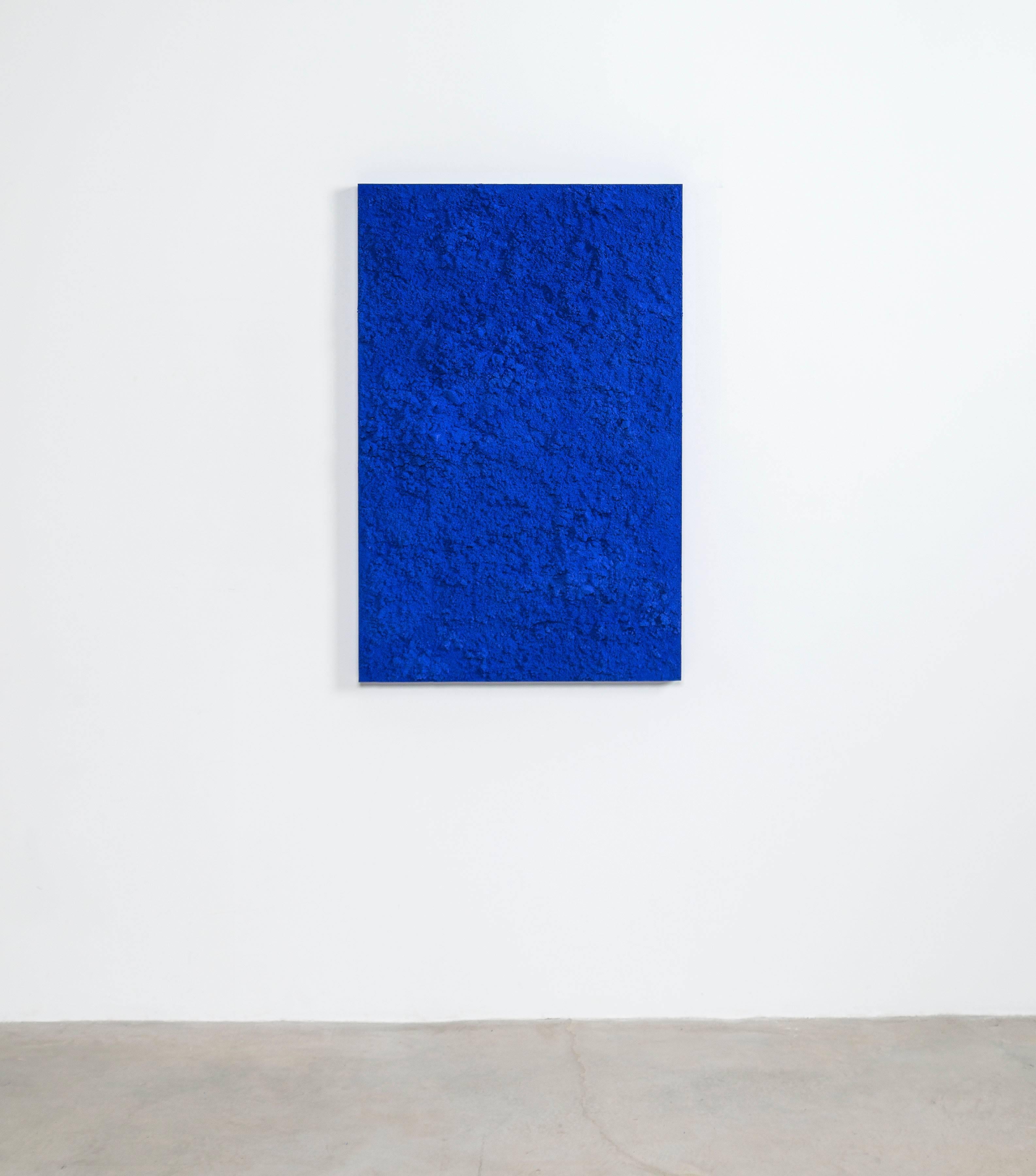 Through a layering of hand-dyed sand, the painting is organically textured and strikingly unadorned. The mass of bright blue granules come together in a terrain-like abstraction.
