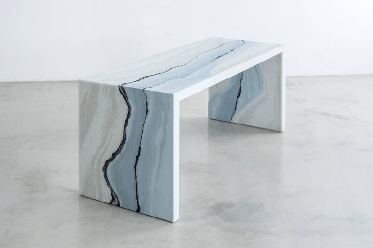 A layering of powdered glass and sand, the made-to-order desk consists of gradients of tones and textures suggesting layers of earth, mountain ranges, otherworldly skies and bodies of water. The hand-dyed granules are stratified with delicate veins