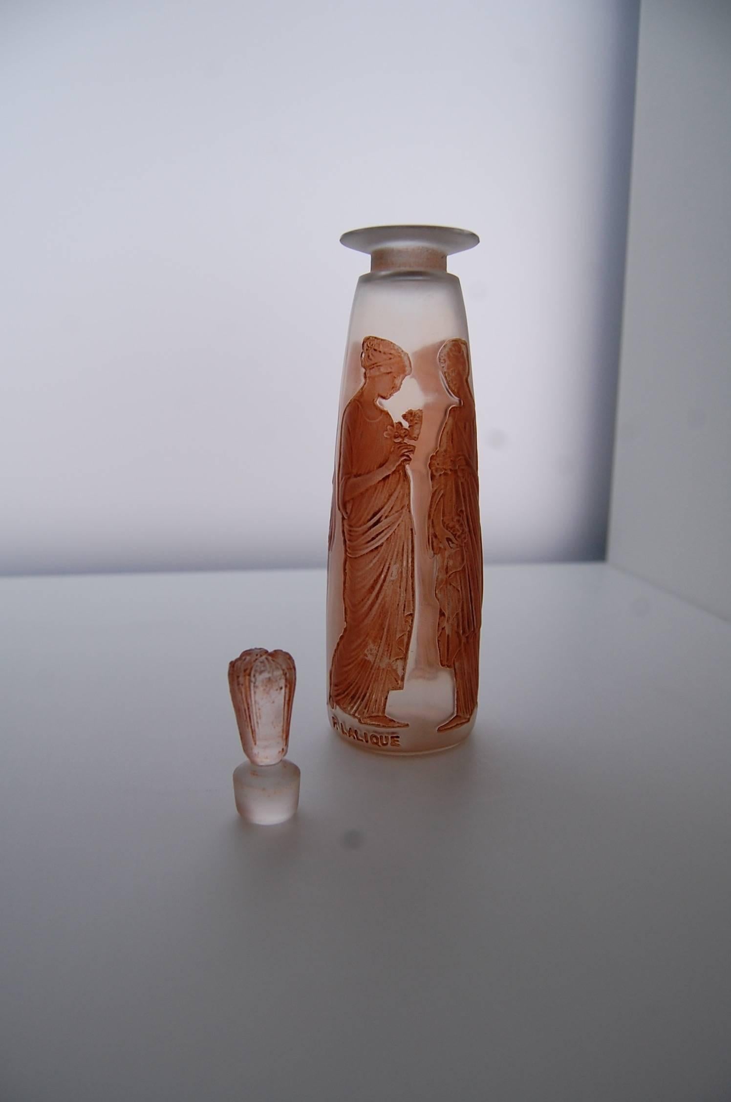 This perfume bottle was one of the first Rene Lalique designed for French perfumer Francois Coty in 1910. Pressed air glass was blown in a mold thus making a crisp decor. The four maidens are brown patinated and dressed in a Greek antique style. Its