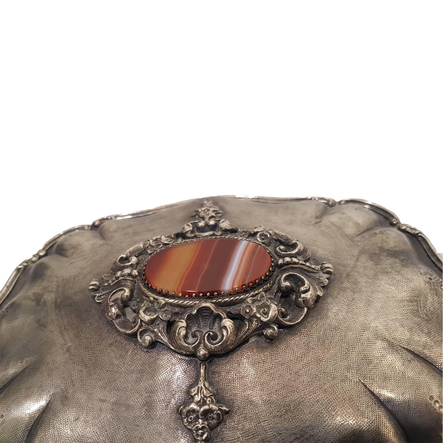 Silver jewel box with entirely engraved with burin, with bent profile, floral decorations, hinged lid with a red agate in the middle of the top.

Inside the box, we can read: “ A Elena Rizzieri, il teatro Sociale di Rovigo che la vide debuttante e
