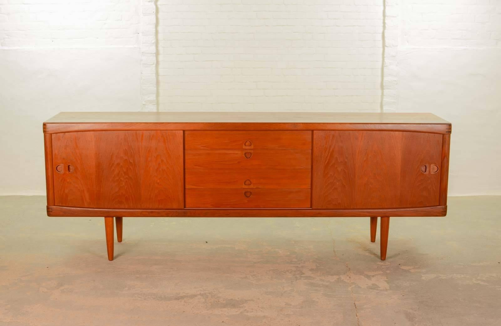 This beautiful large high quality finished Danish sideboard or credenza is designed by H.W. Klein for Bramin in the 1960s. It features on both sides two identical sliding doors with four drawers in between. All with nicely shaped subtle detailed
