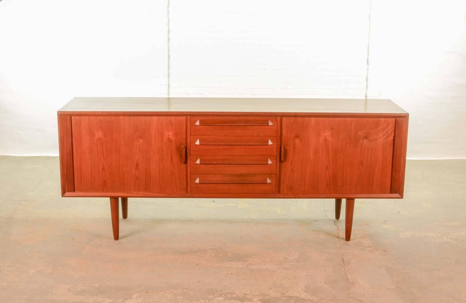 Danish teak credenza designed by Ib Kofod-Larsen in the 1960s for Faarup Mobelfabrik. Teak with rich dimensional detailing. Tambour doors on the left and right glide open to adjustable shelves. Furthermore it contains four drawers in the middle with