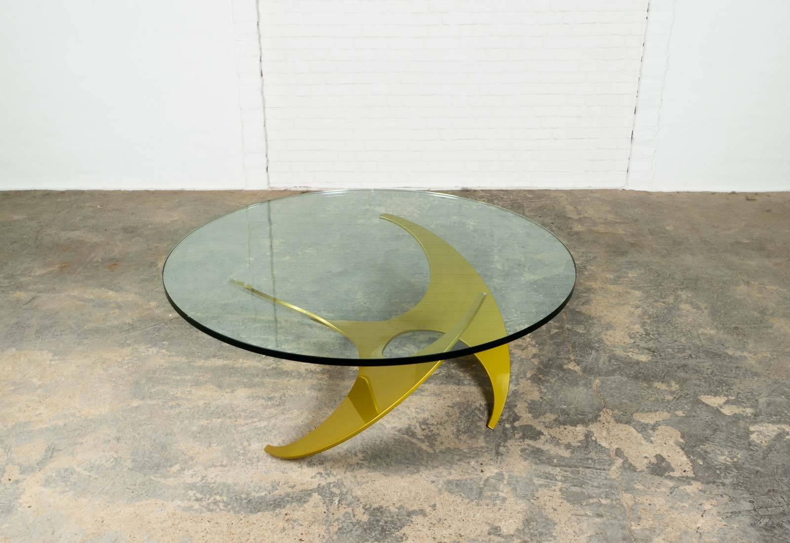 Mid-Century 'Propeller' cocktail table designed by Knut Hesterberg for Ronald Schmitt in 1964, Germany. The table has a gold lacquered aluminium base and a very solid glass round top. The gold anodized aluminium base is hand sculptured into a