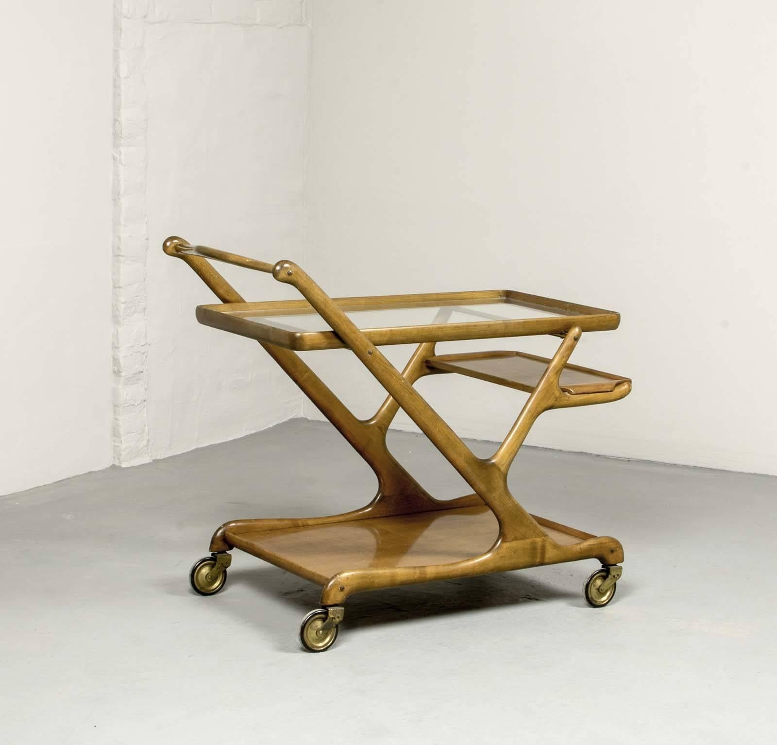 Elegant original walnut Italian serving bar / tea trolley designed in Italy in the 1950s by Cesare Lacca for Cassina. This beautiful movable bar features a glass top on a walnut frame and brass wheels, including a loose serving tray.
The trolley is